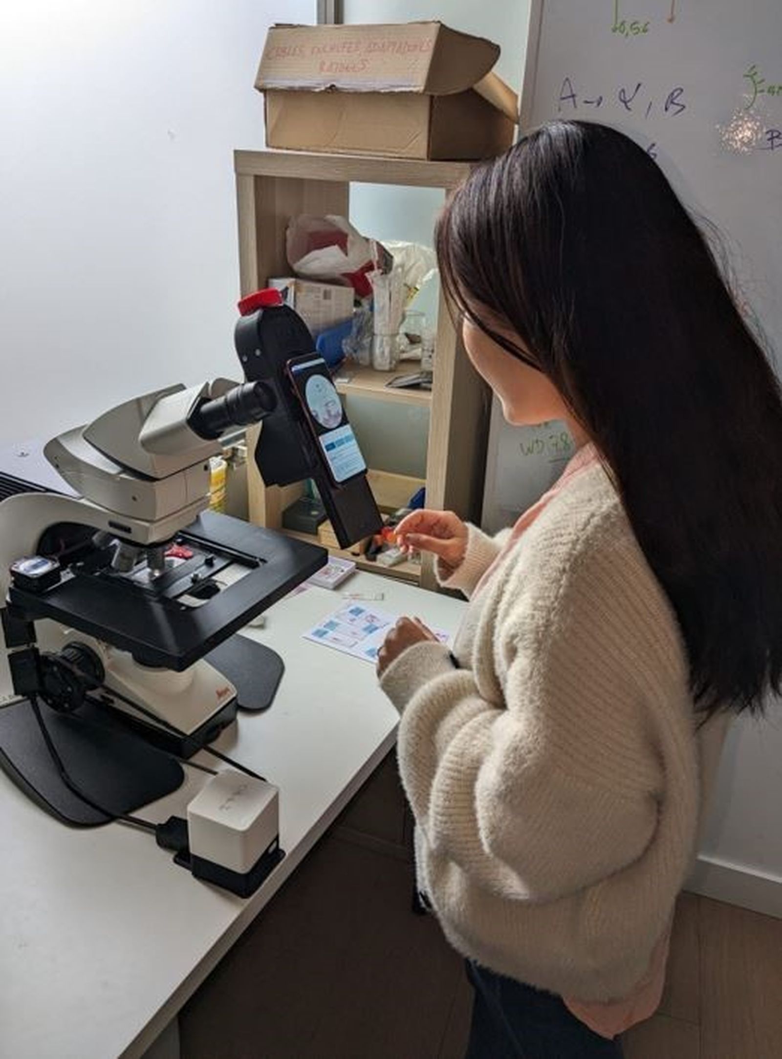 Una investigadora utiliza un móvil con un microscopio para el cribado de parásitos