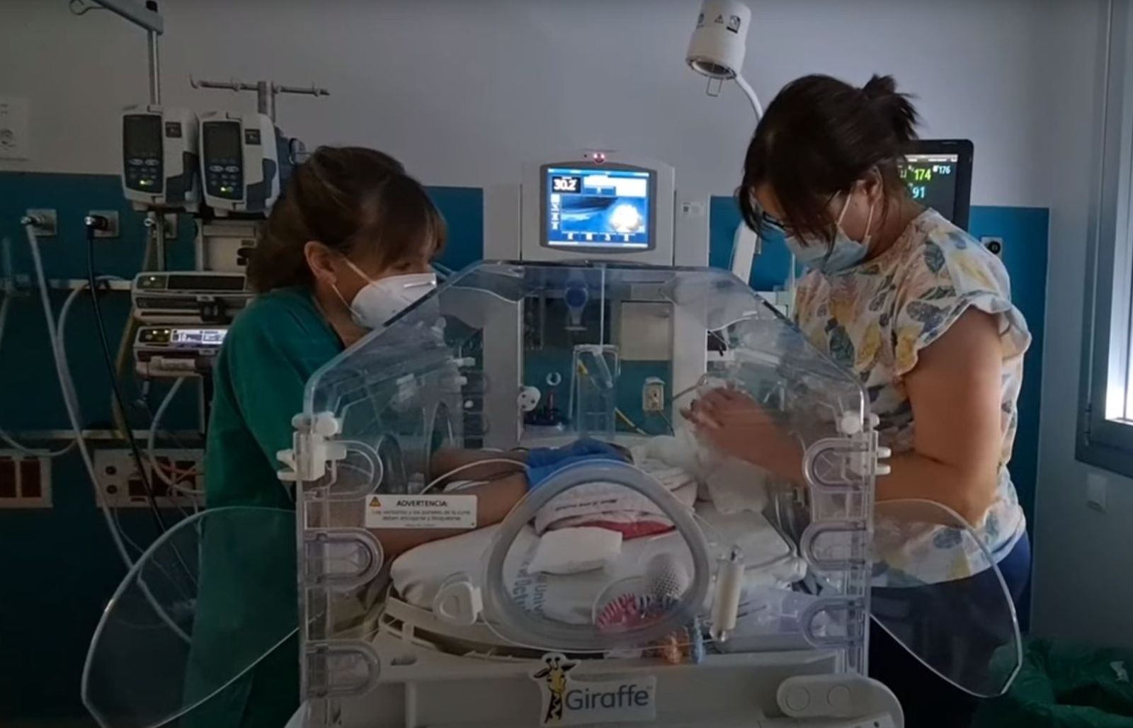 Una enfermera y la madre atienden a un bebé en una incubadora