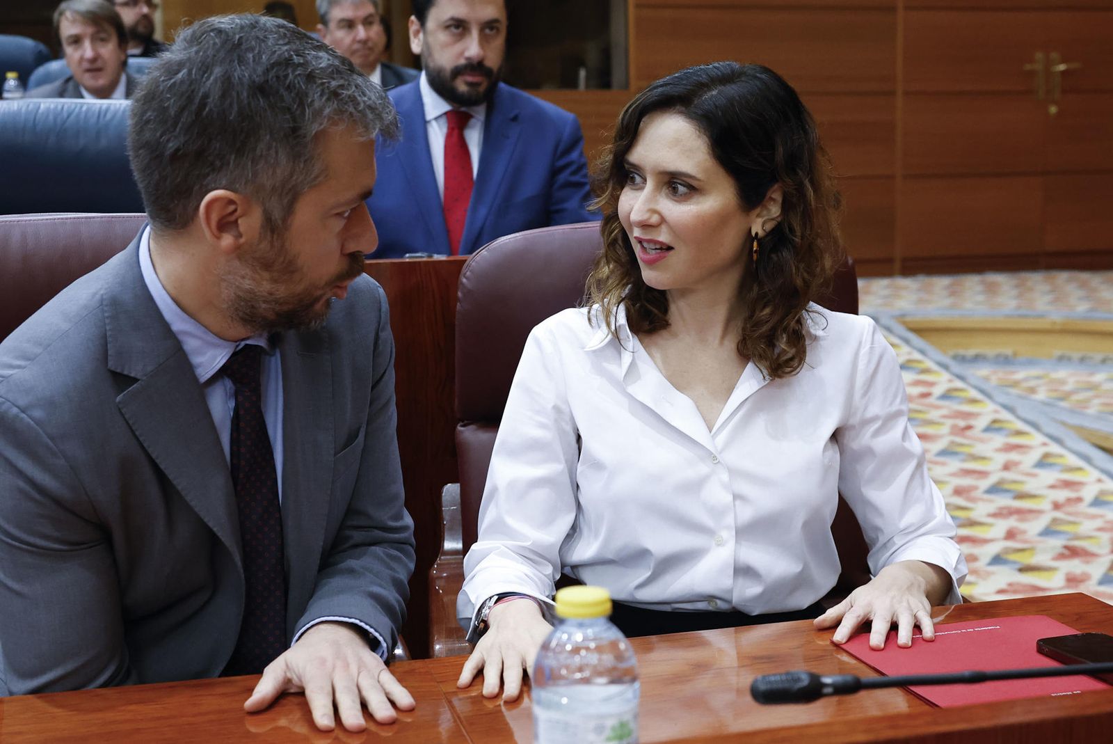 La presidenta de la Comunidad de Madrid, Isabel Díaz Ayuso (d), conversa con el consejero de Presidencia, Justicia y Administración Local, Miguel Ángel García Martín