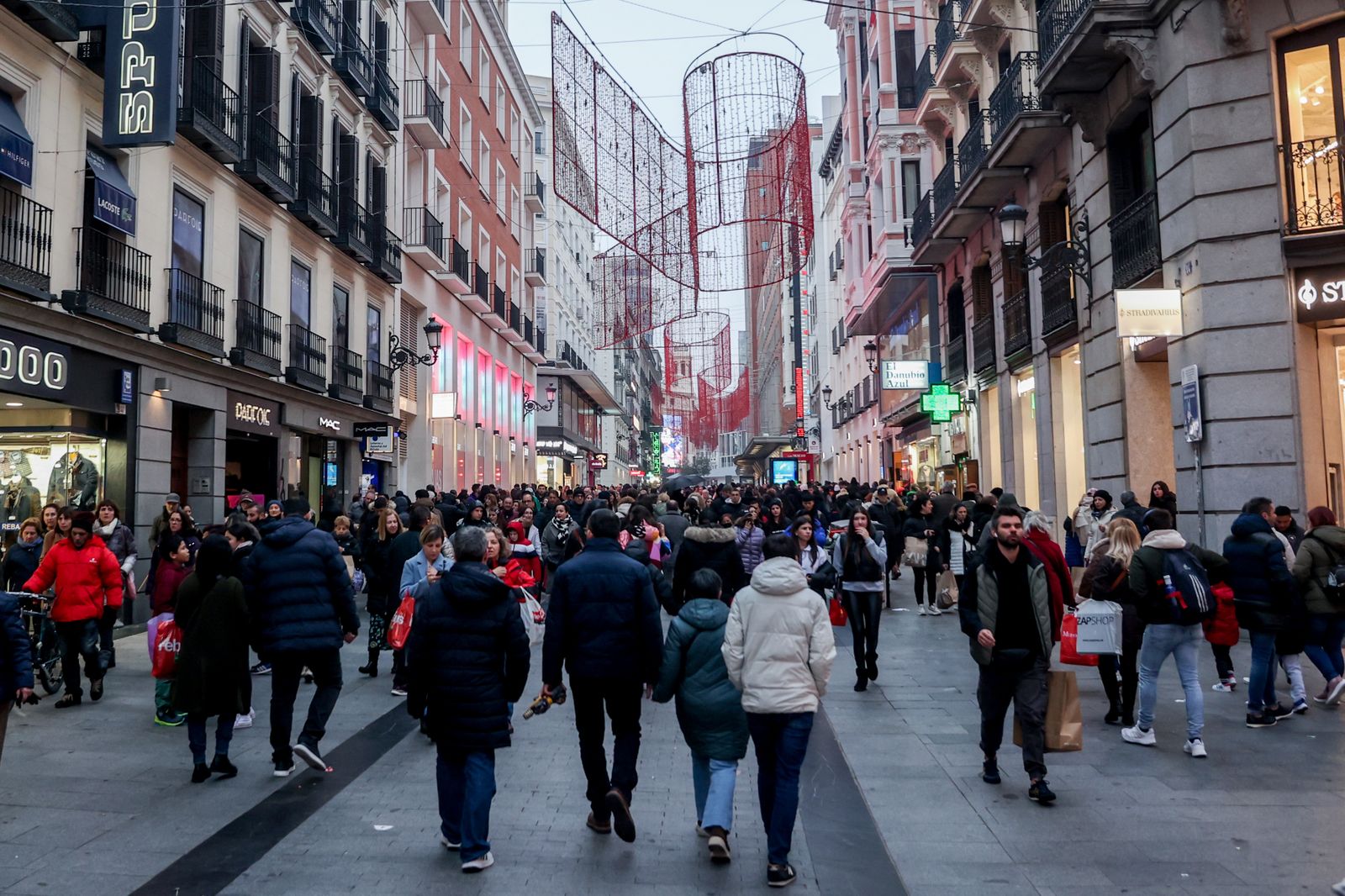 Cientos de personas, con compras, en la calle comercial de Preciados