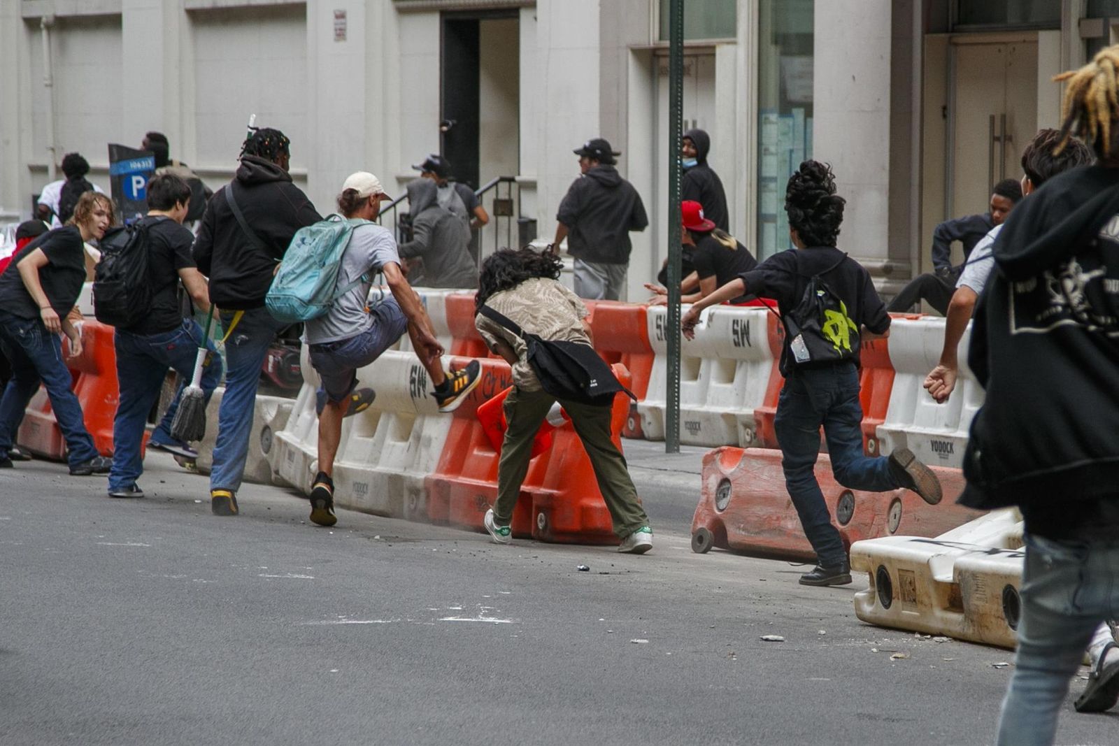 Un grupo de personas derriba a patadas las barreras de construcción durante los disturbios