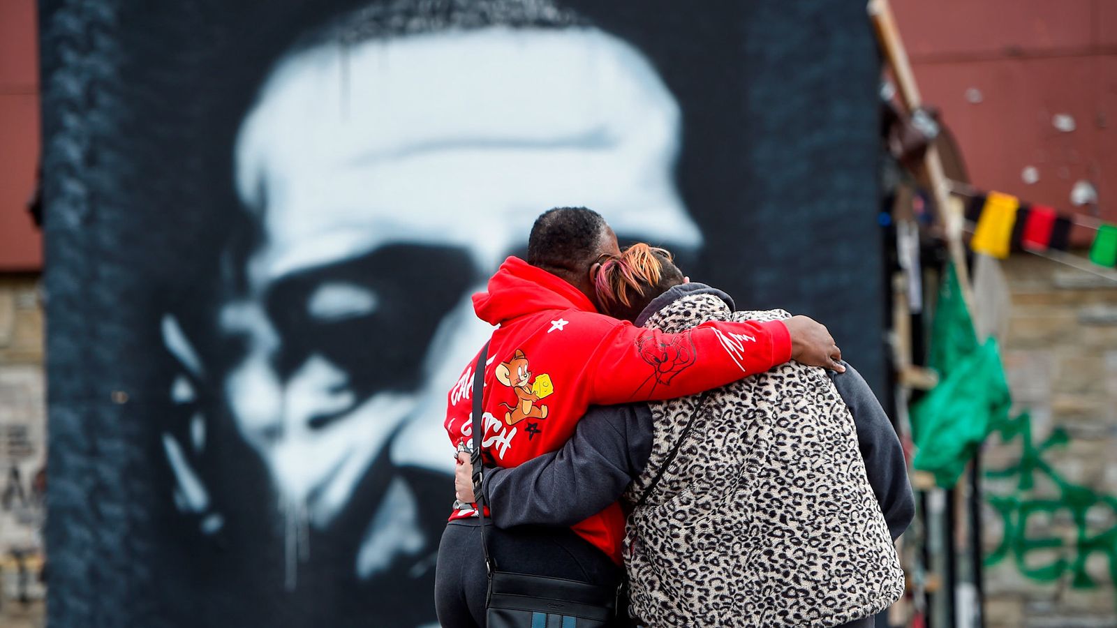 Una pareja se abraza frente al retrato de George Floyd