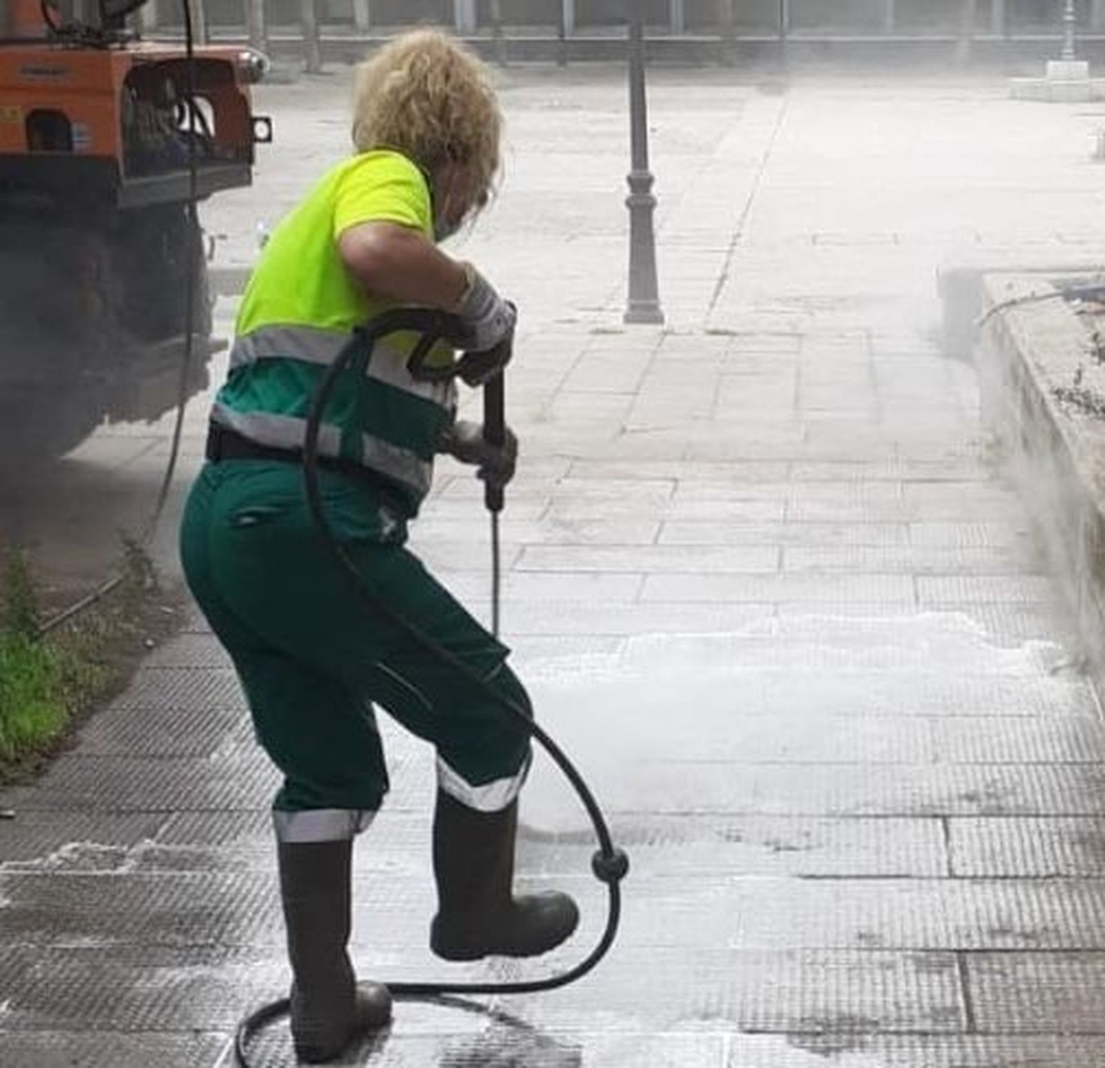 Una operaria del servicio de limpieza de Alcalá baldea una calle