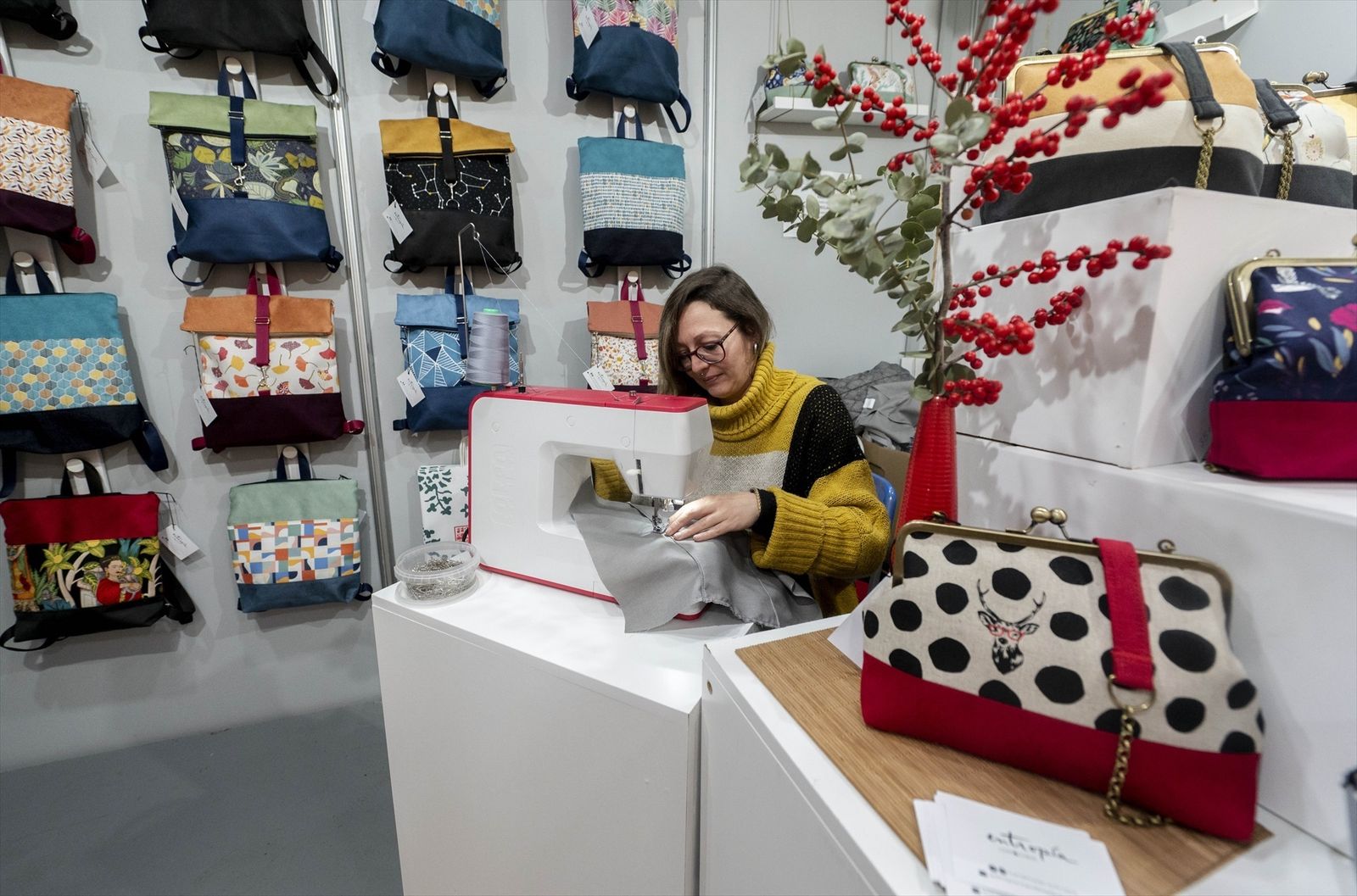 La artista de 'Entropía', Sonia Peña, cose bolsos artesanos en su puesto en la 36º edición de la Feria Mercado de Artesanía, en el Paseo de Recoletos