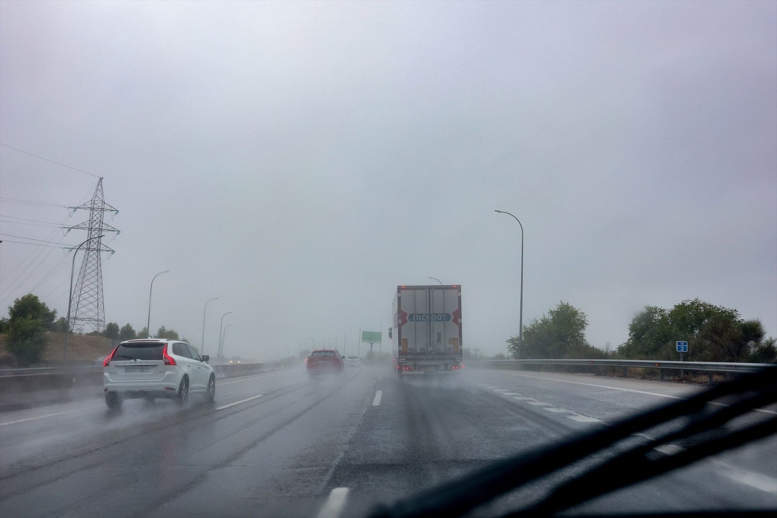 Varios vehículos circulan bajo la lluvia en Madrid