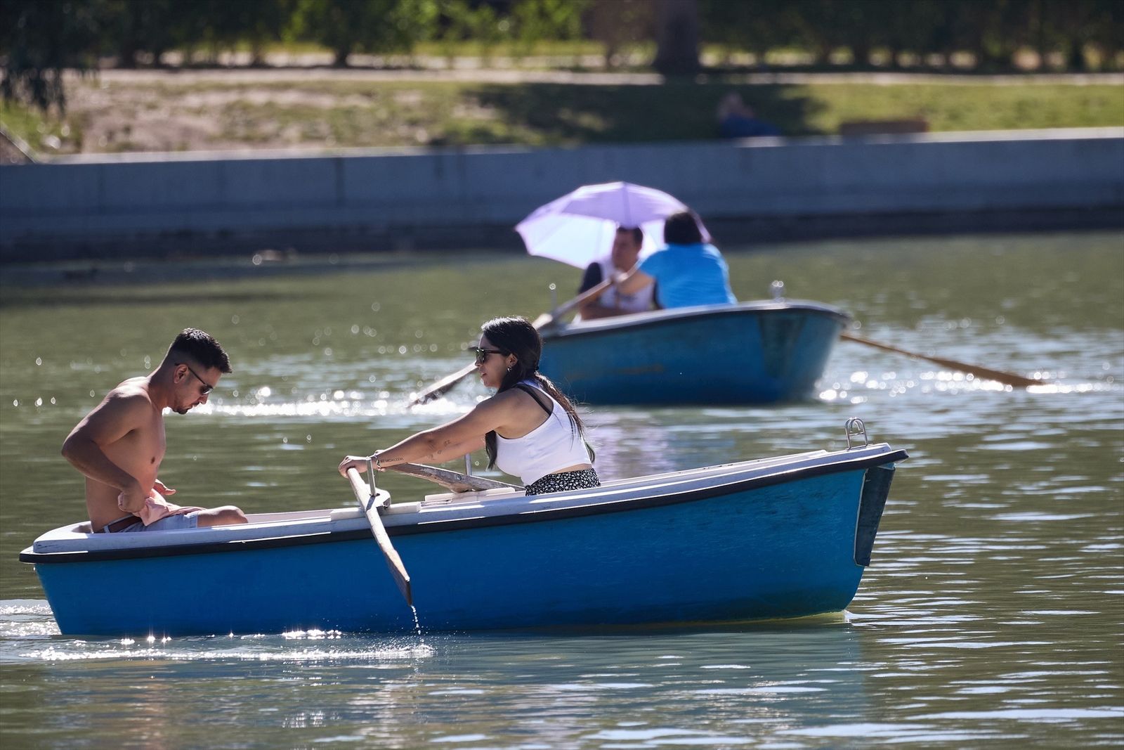 Dos personas en una barca del largo del parque de El Retiro durante la ola de calor