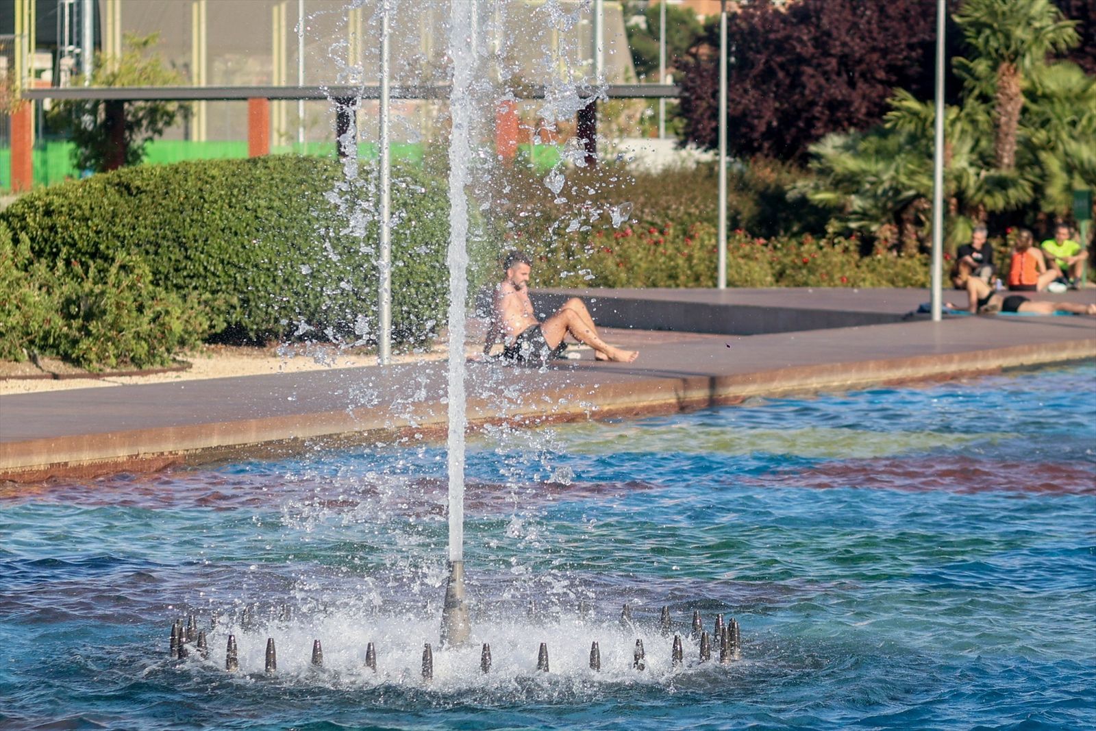 Varias personas se refrescan durante la primera ola de calor, en el parque del Canal de Isabel II