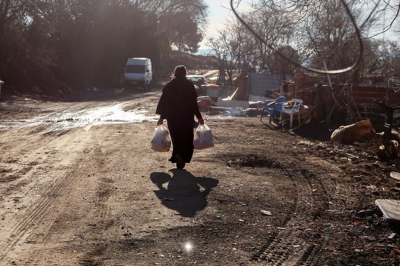 Una mujer camina por la Cañada Real con bolsas que ha recogido en la entrega de regalos y alimentos