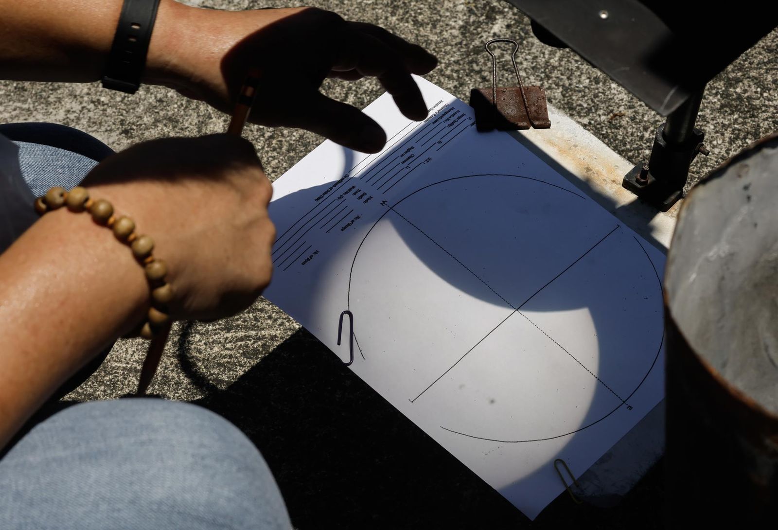 Un especialista de la oficina meteorológica ve un eclipse solar híbrido parcial reflejado en una hoja de datos con el uso de un telescopio en un observatorio astronómico en Quezon City, Metro Manila, Filipinas, el 20 de abril de 2023