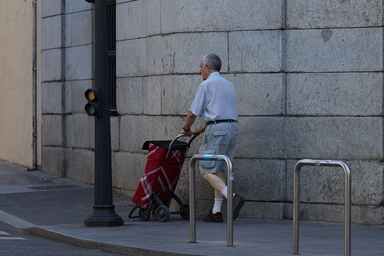 Una persona mayor camina con un carrito por una calle de Madrid