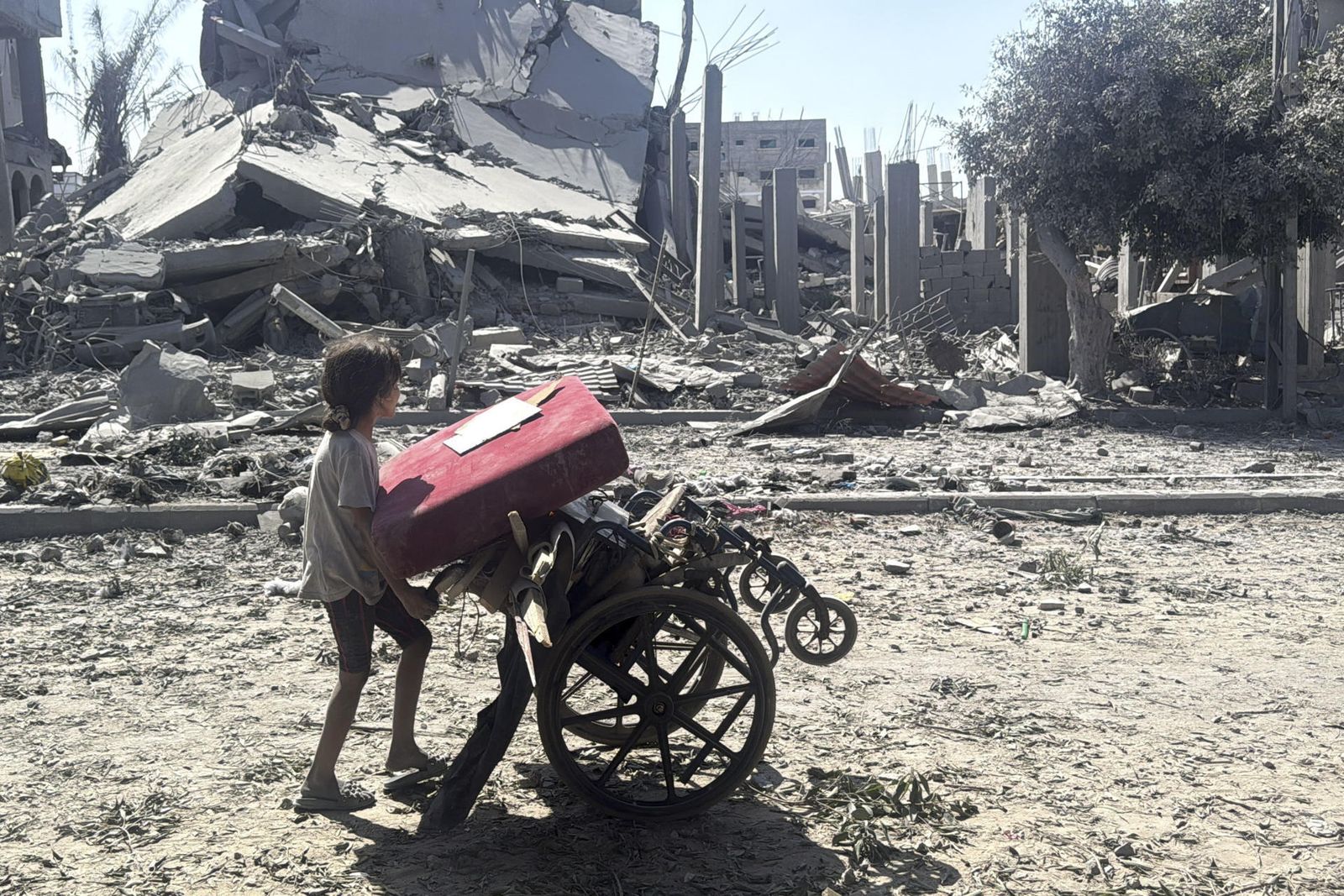 Una niña carga con objetos en una silla de ruedas, en Ciudad de Gaza