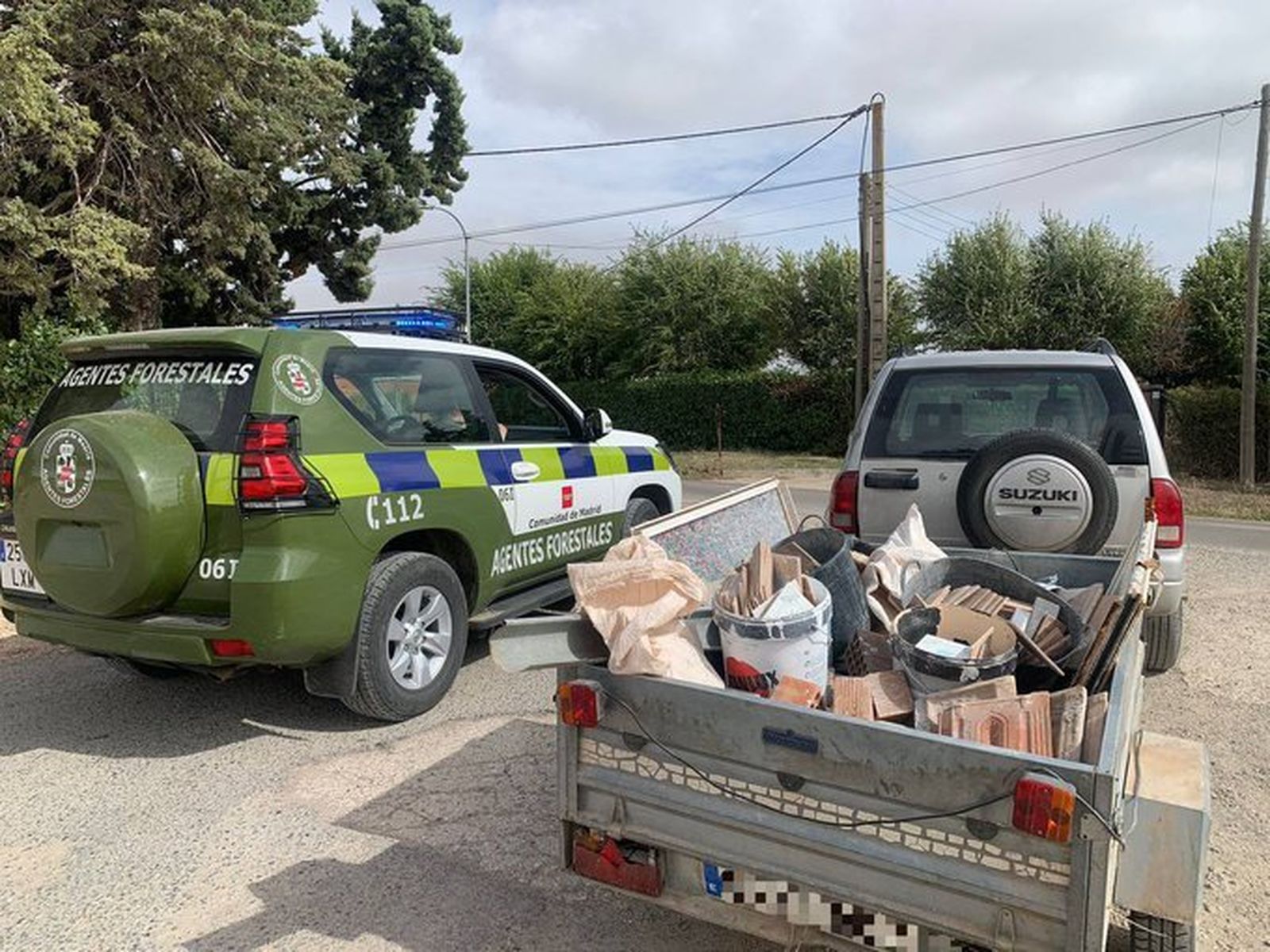 Agentes forestales junto a un vehículo cargado con restos de obra