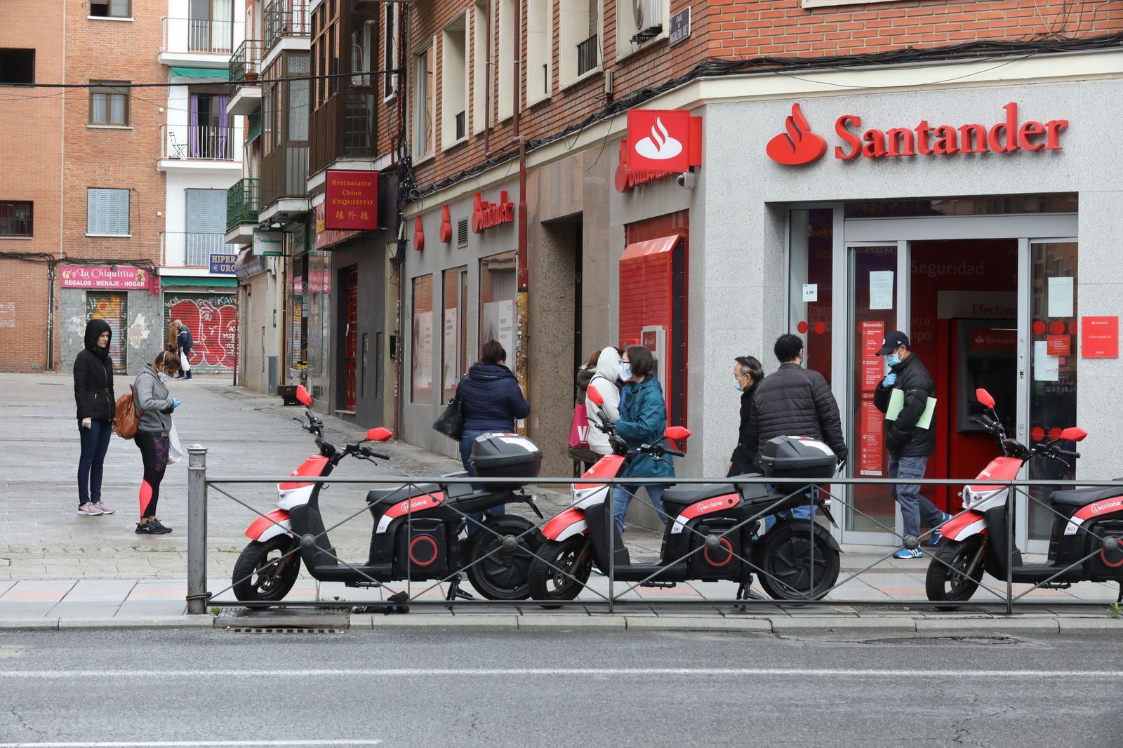 Personas esperan a las puertas de una oficina del Banco Santander