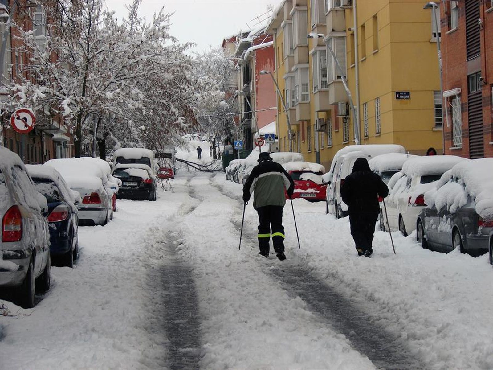 Dos personas caminan entre la nieve en una calle de Madrid