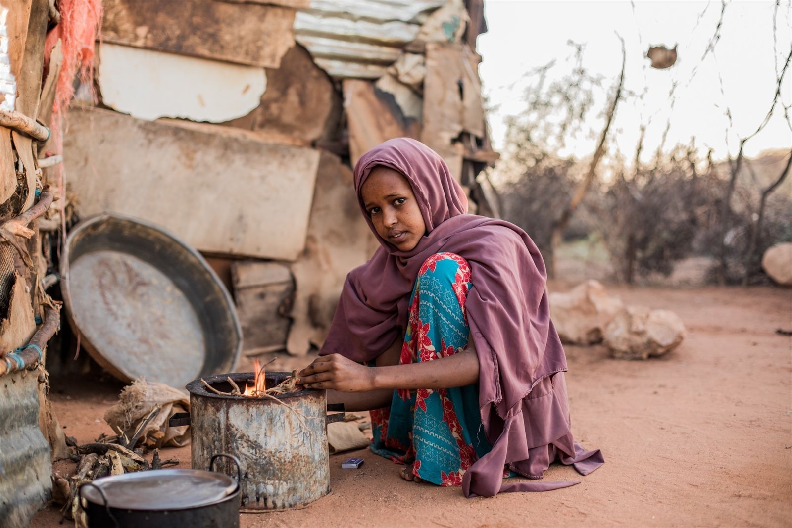 Una joven enciende una cocina de leña en una aldea de Somalia