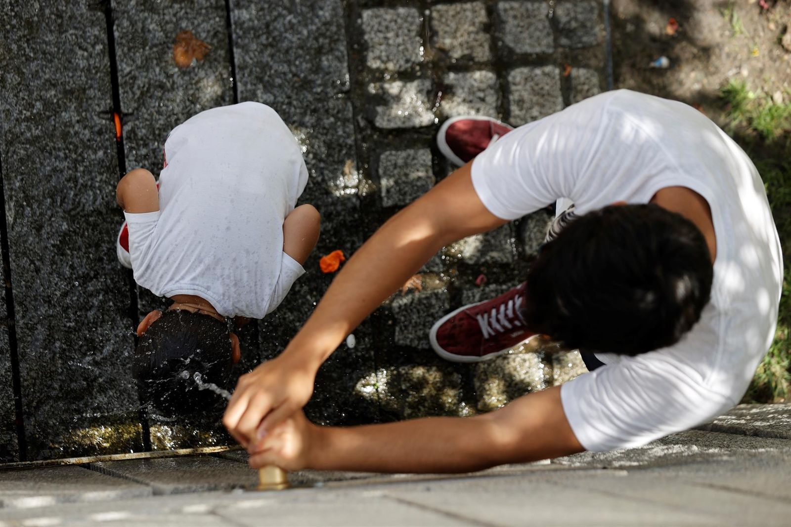 En Madrid se alcanzarán los 43 grados centígrados en regiones del sur, como Aranjuez. Una fuente se convierte en todo un tesoro que bien merece una buena parada. Este padre aprovecha para refrescar a su hijo.