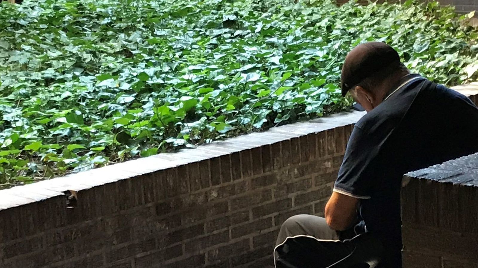 Una persona mayor sentada en el exterior de una zona residencial