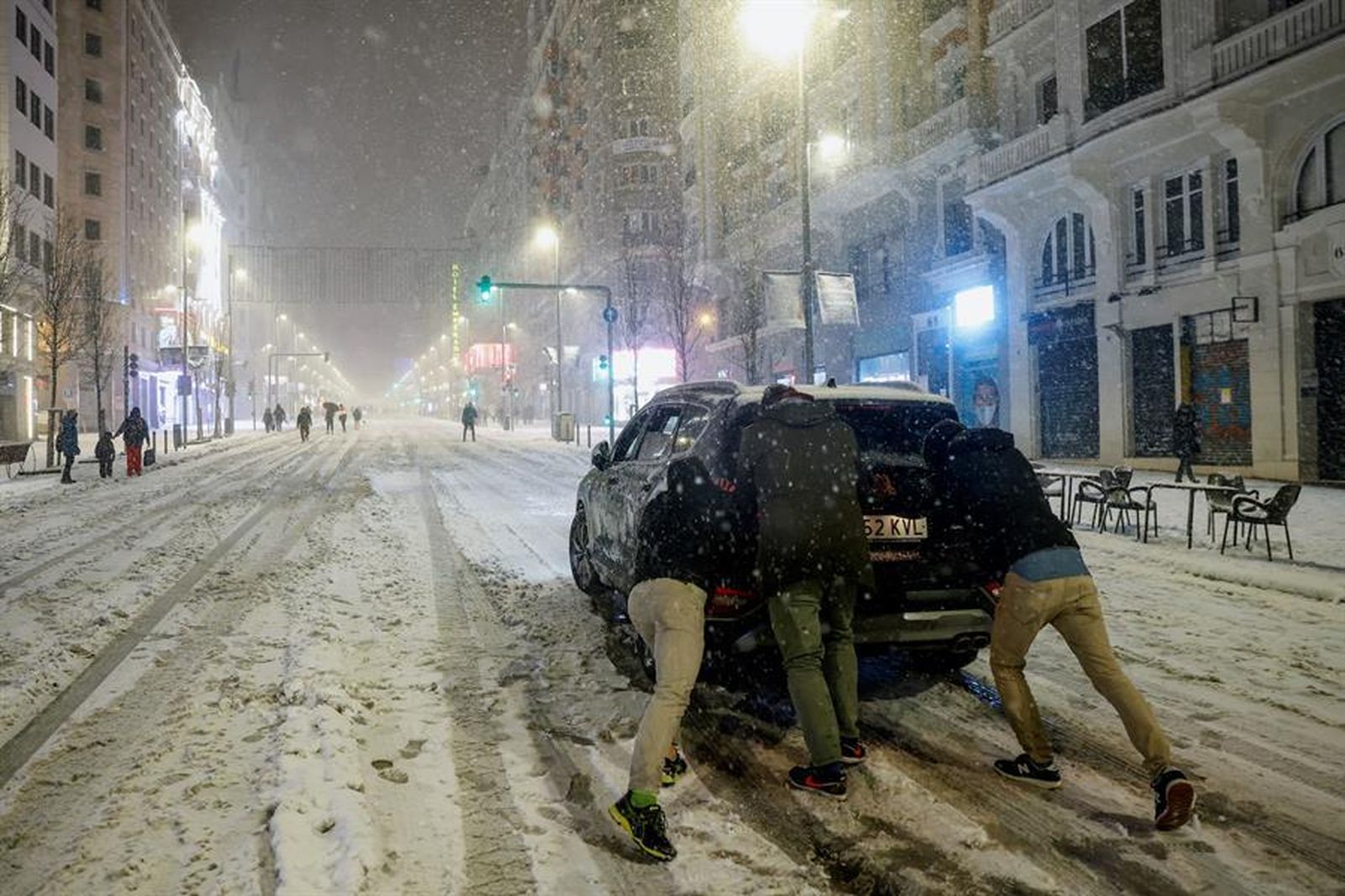Jóvenes empujan un coche en plena Gran Vía bajo la nieve