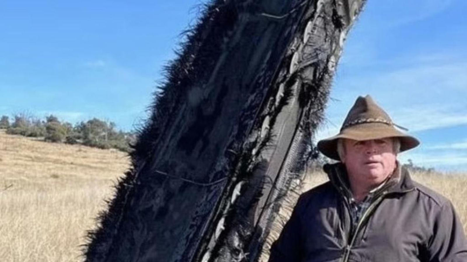 El australiano Mick Miner  junto a la pieza de la nave SpaceX que cayó en su granja