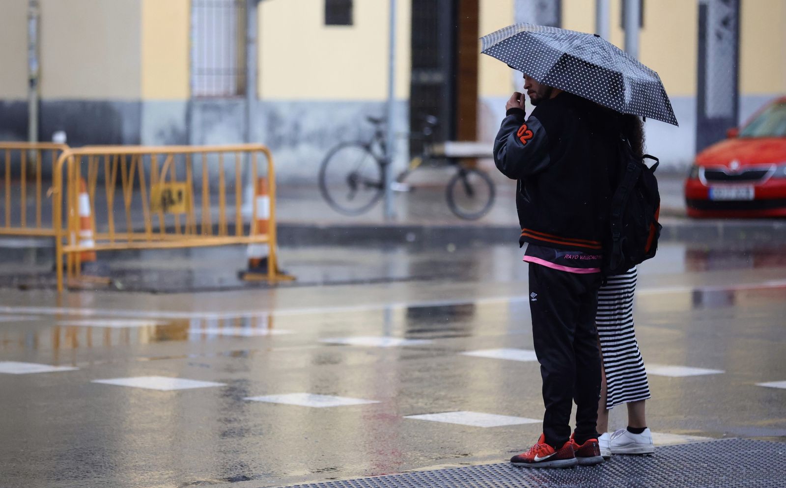 Una pareja se refugia de la lluvia en Madrid