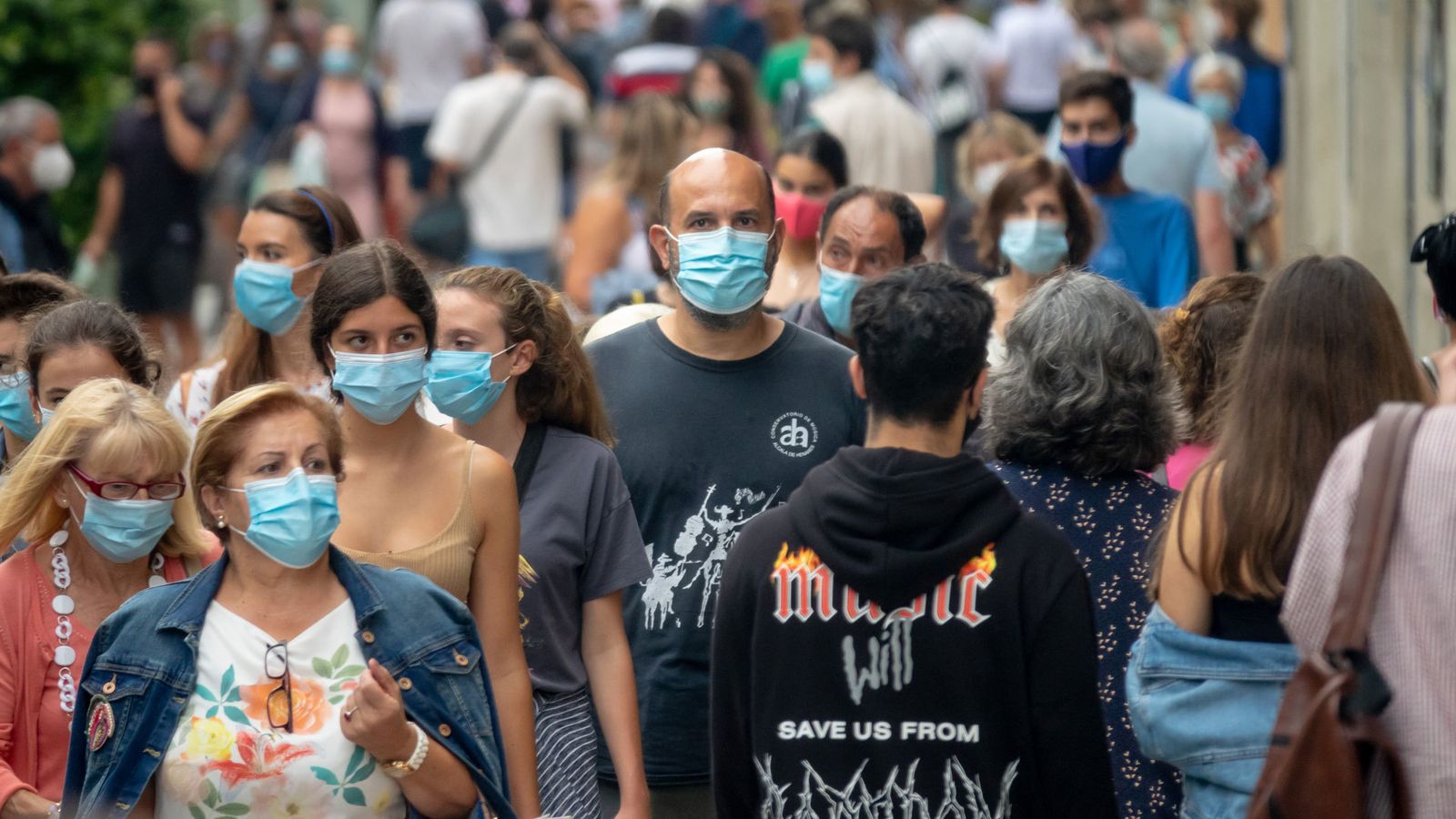 Un grupo de personas pasean por la calle protegidos con mascarillas