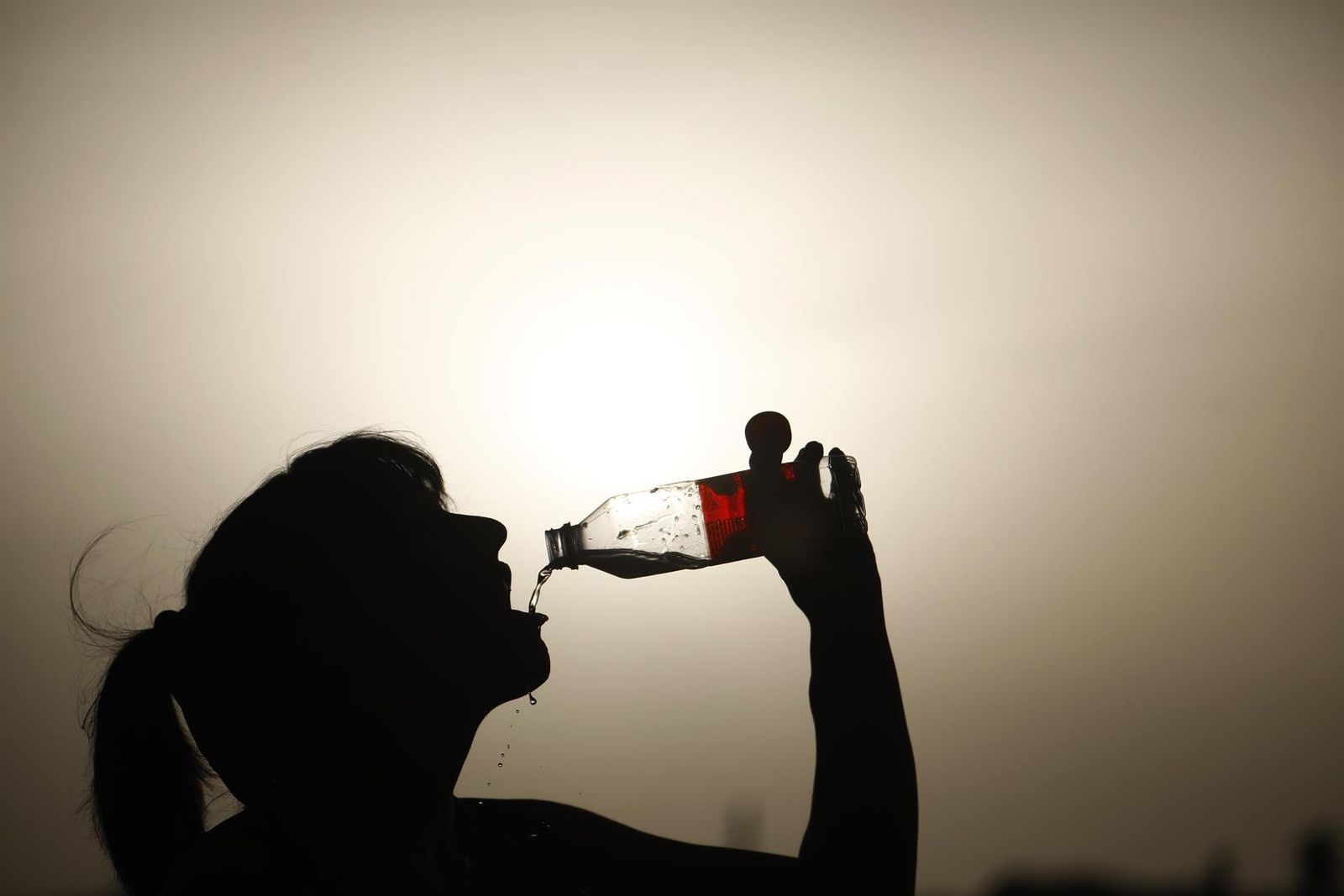 Mujer bebe agua para sofocar el calor