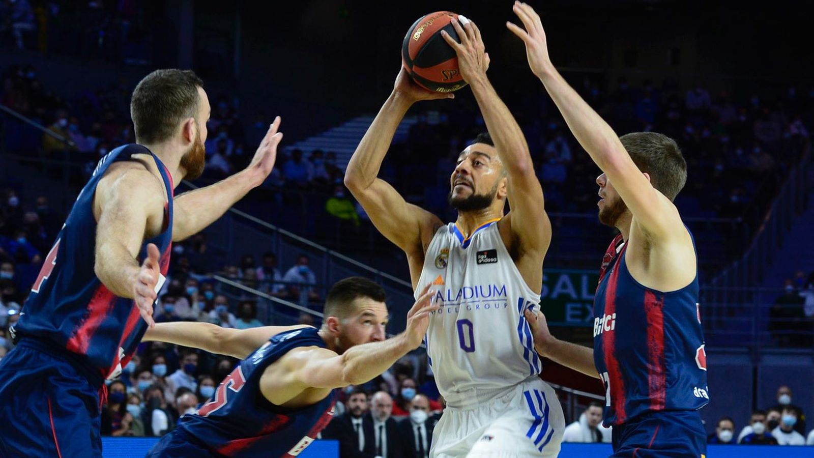 El base del Real Madrid Nigel Williams-Goss entra a canasta entre Matt Costello y Rokas Giedraitis durante el partido de la jornada 23 de Liga ACB que se juega este domingo en el Palacio de los Deportes de la Comunidad de Madrid