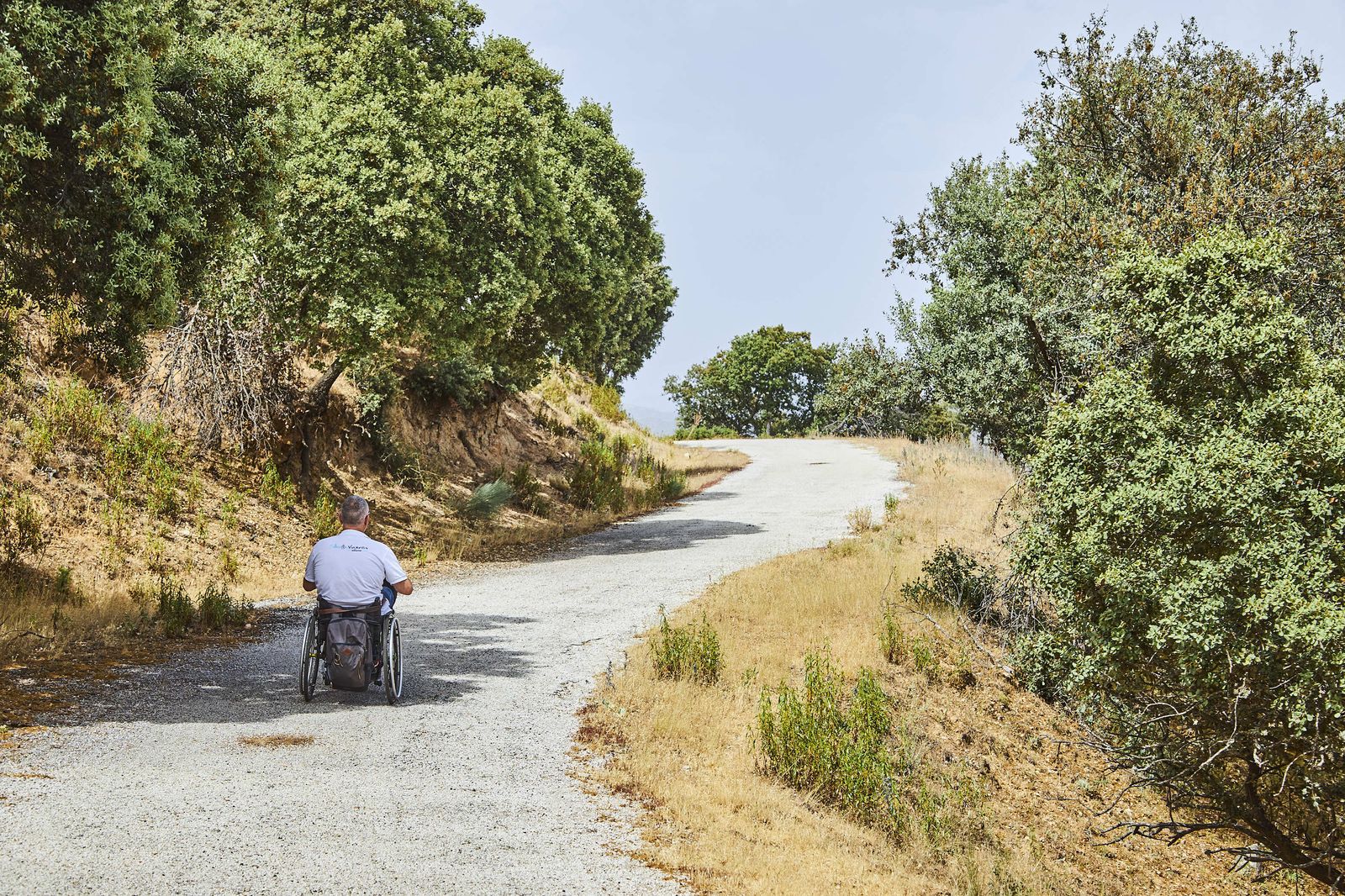 Una persona en silla de ruedas avanza por un camino en el entorno de Redueña