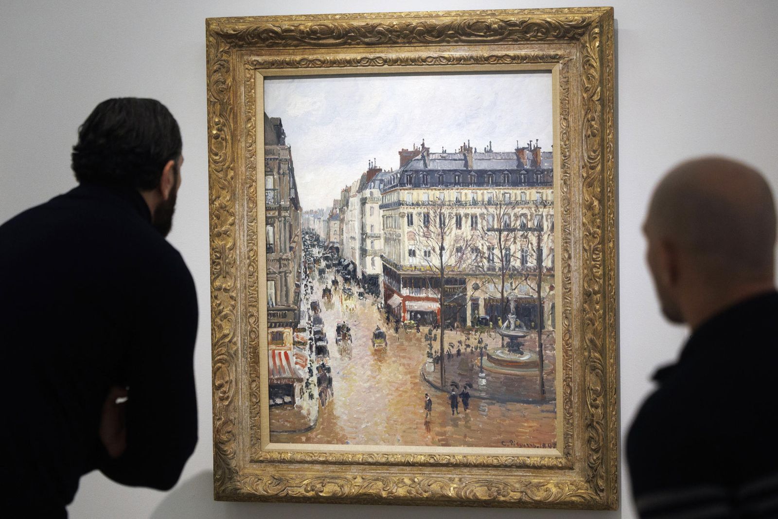 Personas observan el cuadro 'Rue Saint-Honoré por la tarde. Efecto de lluvia', de Camille Pissarro, en el Museo Thyssen-Bornemisza
