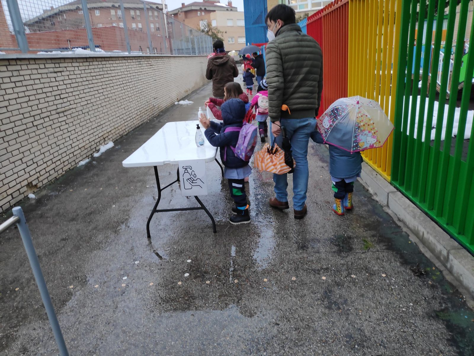 Niños a la entrada de un colegio en mitad de la pandemia y tras la nevada