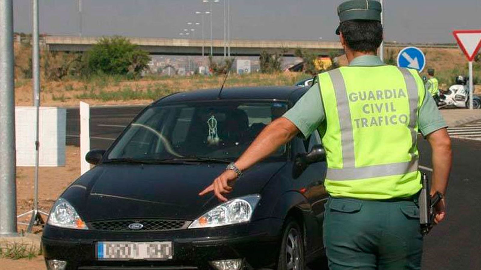 Un agente de la Guardia Civil detiene un vehículo