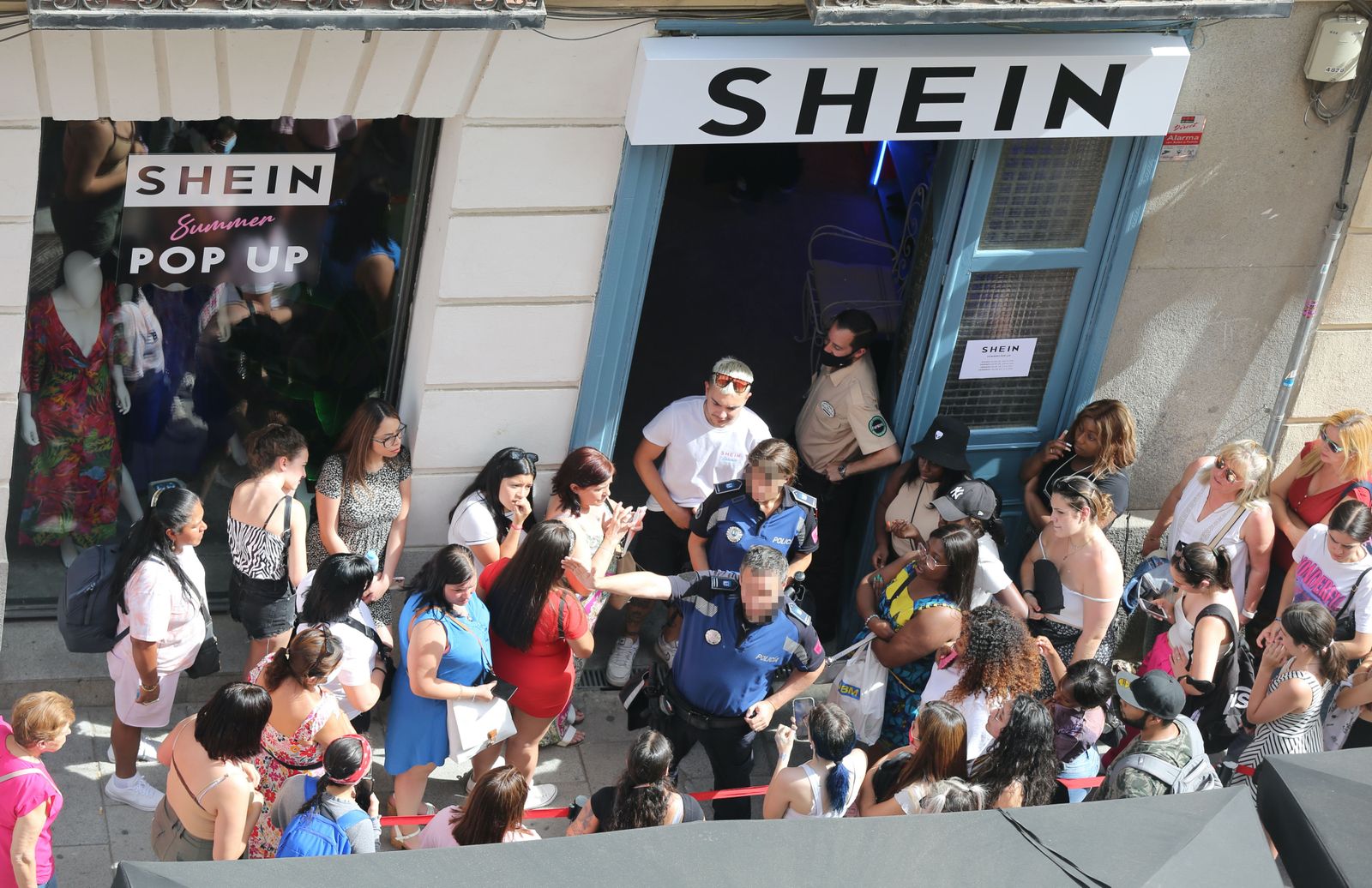 Dos agentes de la Policía Municipal coordinan la cola de gente para entrar a la primera tienda física de SHEIN en Madrid