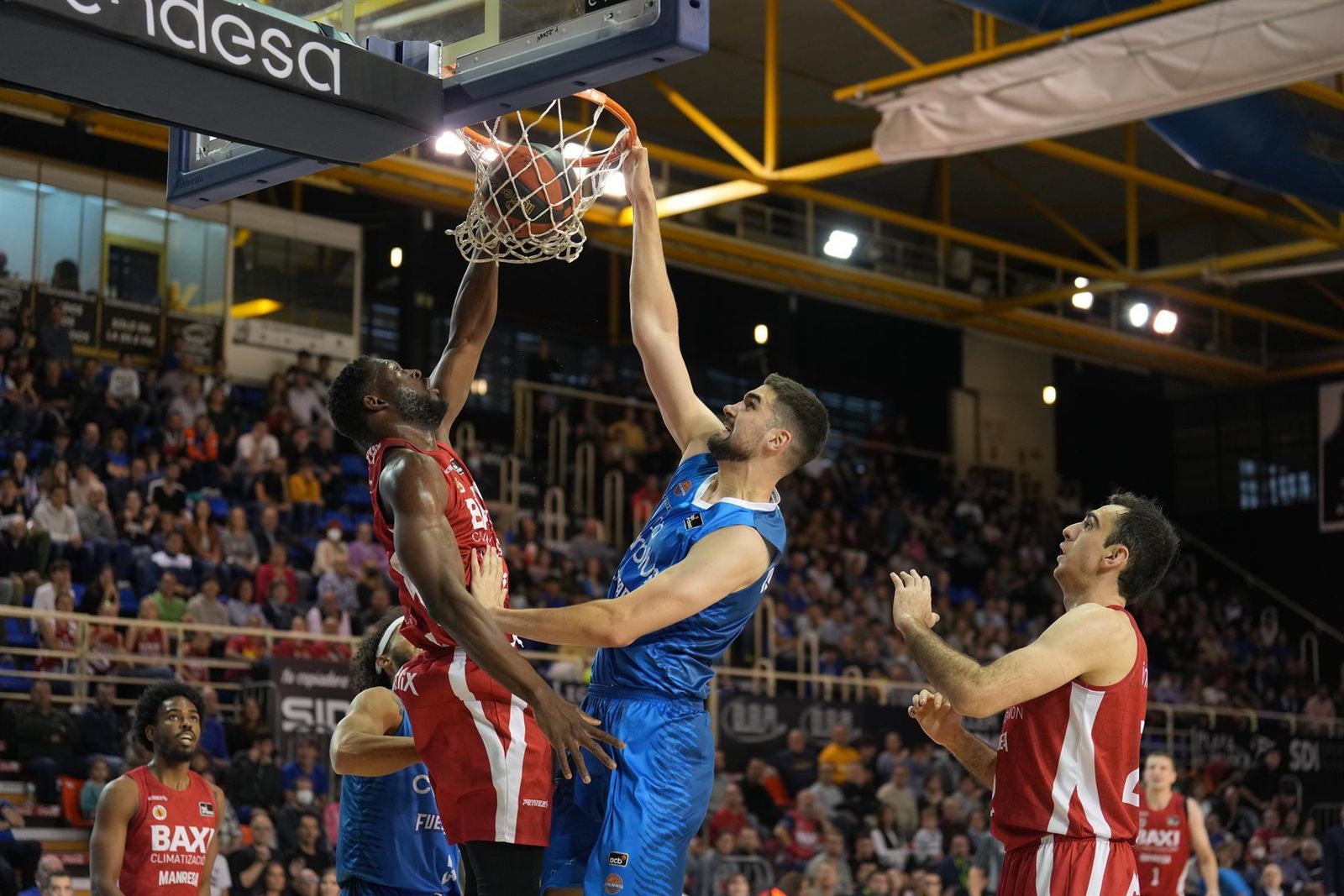 El pívot serbio del Fuenlabrada Dusan Ristic (c) machaca el aro ante el pívot estadounidense del Manresa Marcus Lee