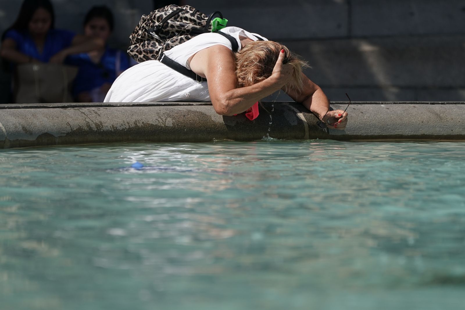 Una mujer se moja la nuca en una fuente