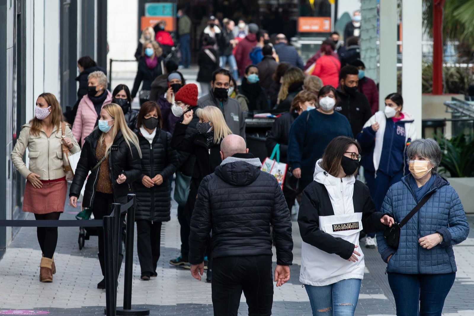 Varias personas en un centro comercial, todas con mascarilla