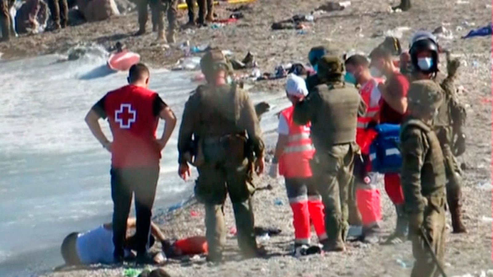 Miembros de Cruz Roja atienden a personas migrantes en la playa de Ceuta