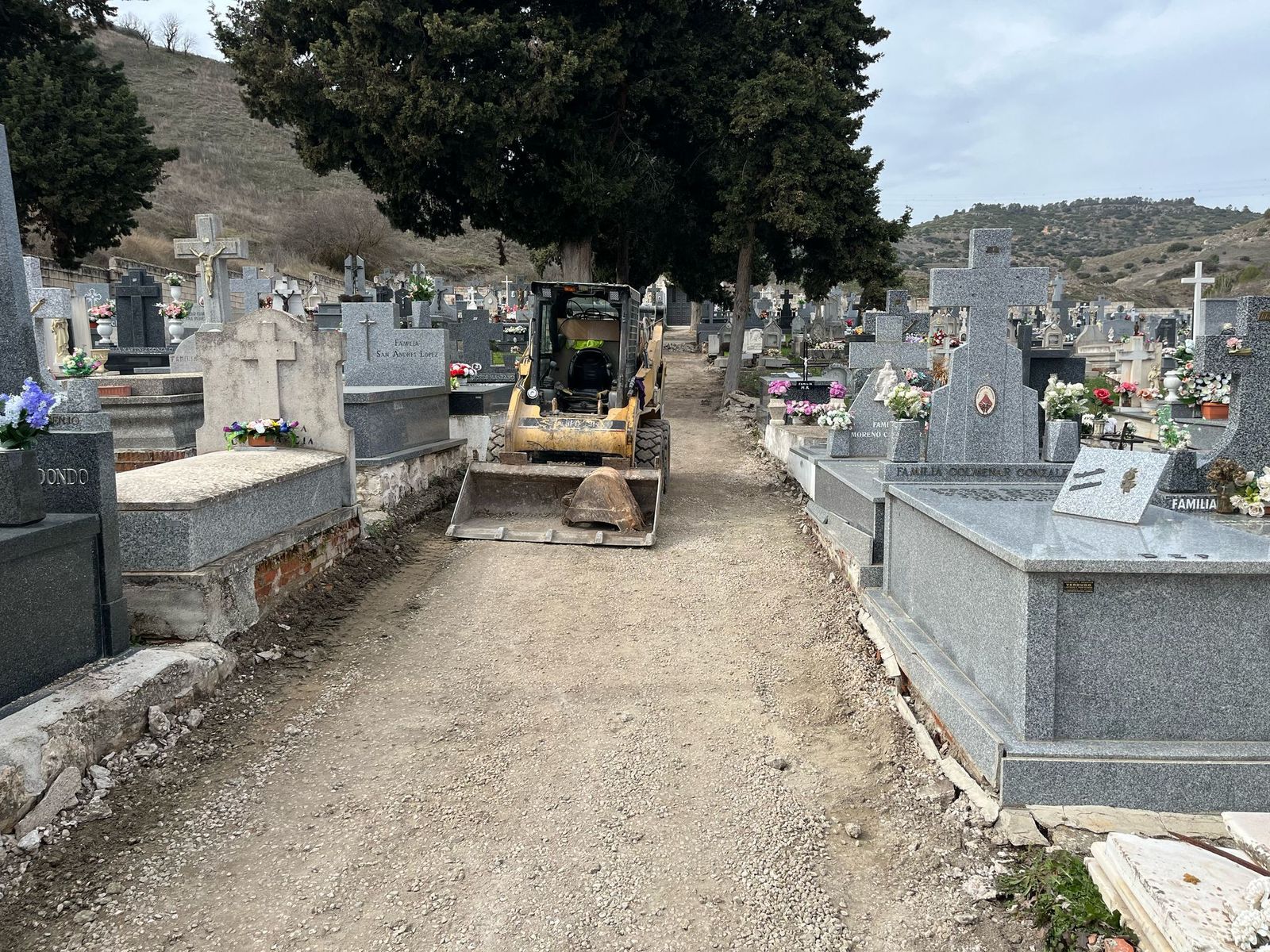 Una excavadora entre las lápidas del cementerio municipal de  Orusco de Tajuña