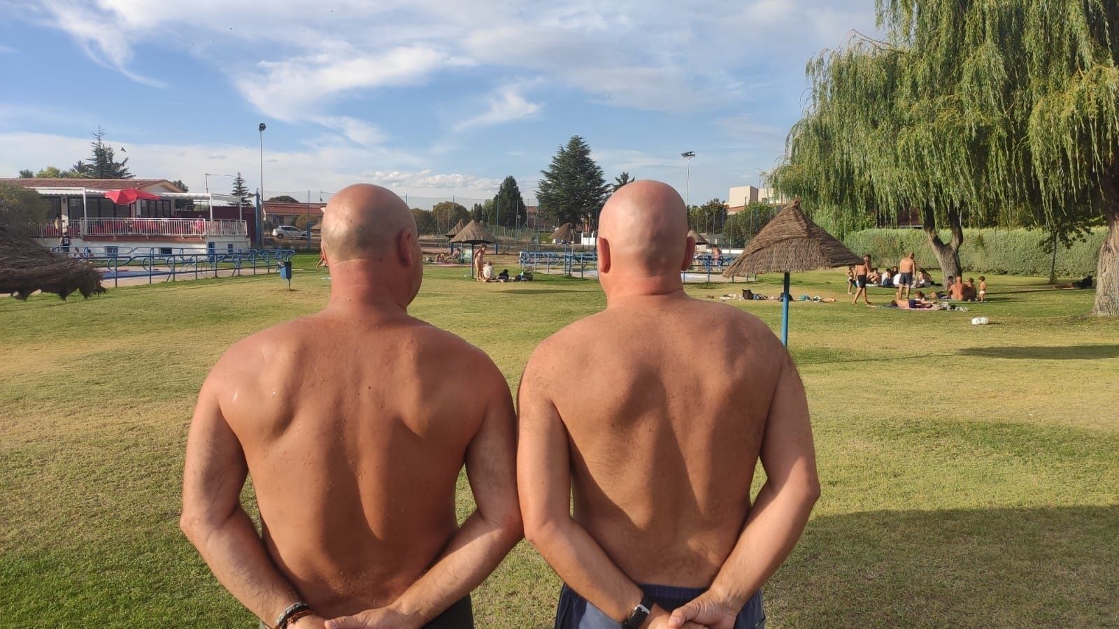 Dos personas calvas en la pradera de una piscina