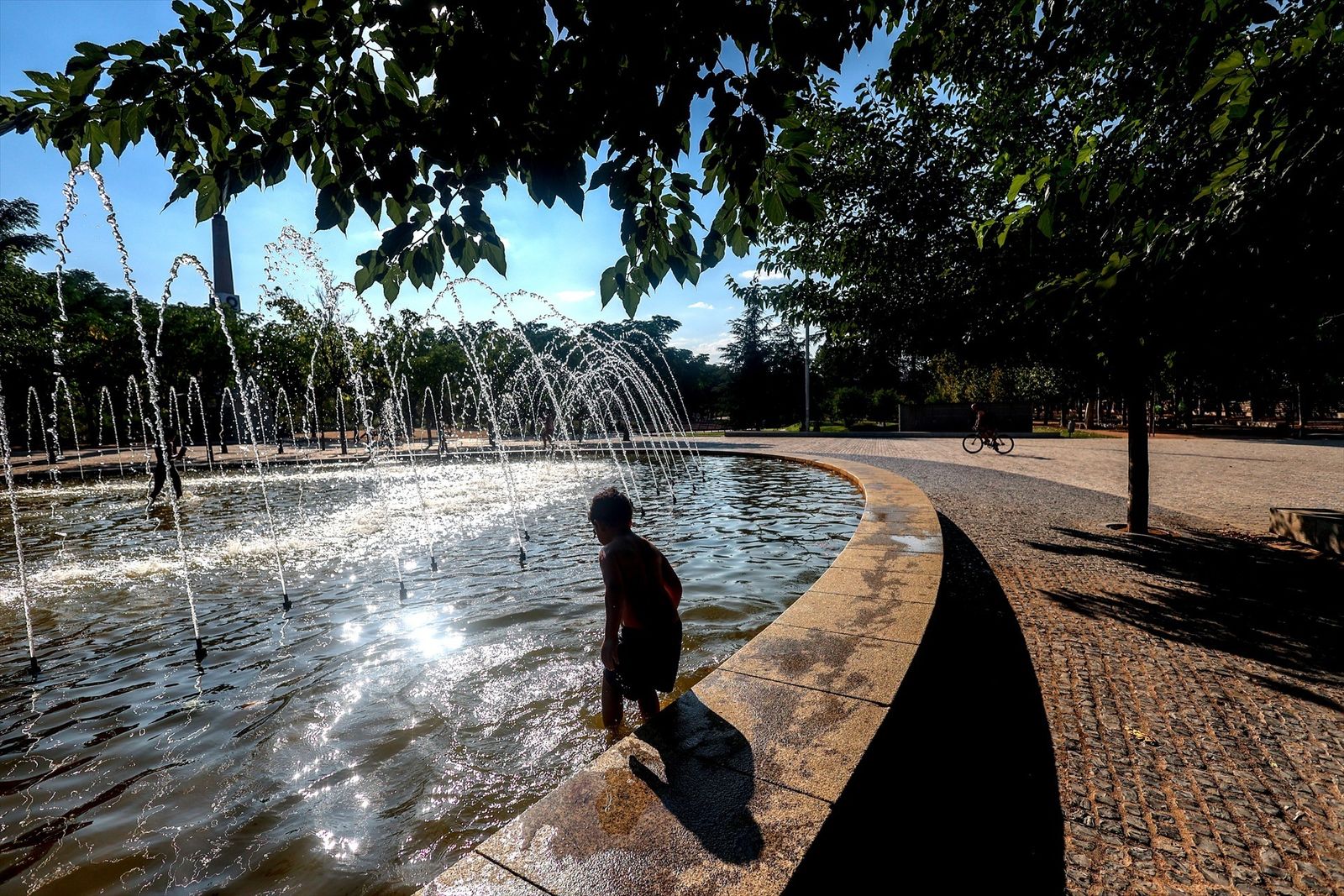 Un niño se refresca en una fuente durante la tercera ola de calor en Madrid, en el parque Madrid Río