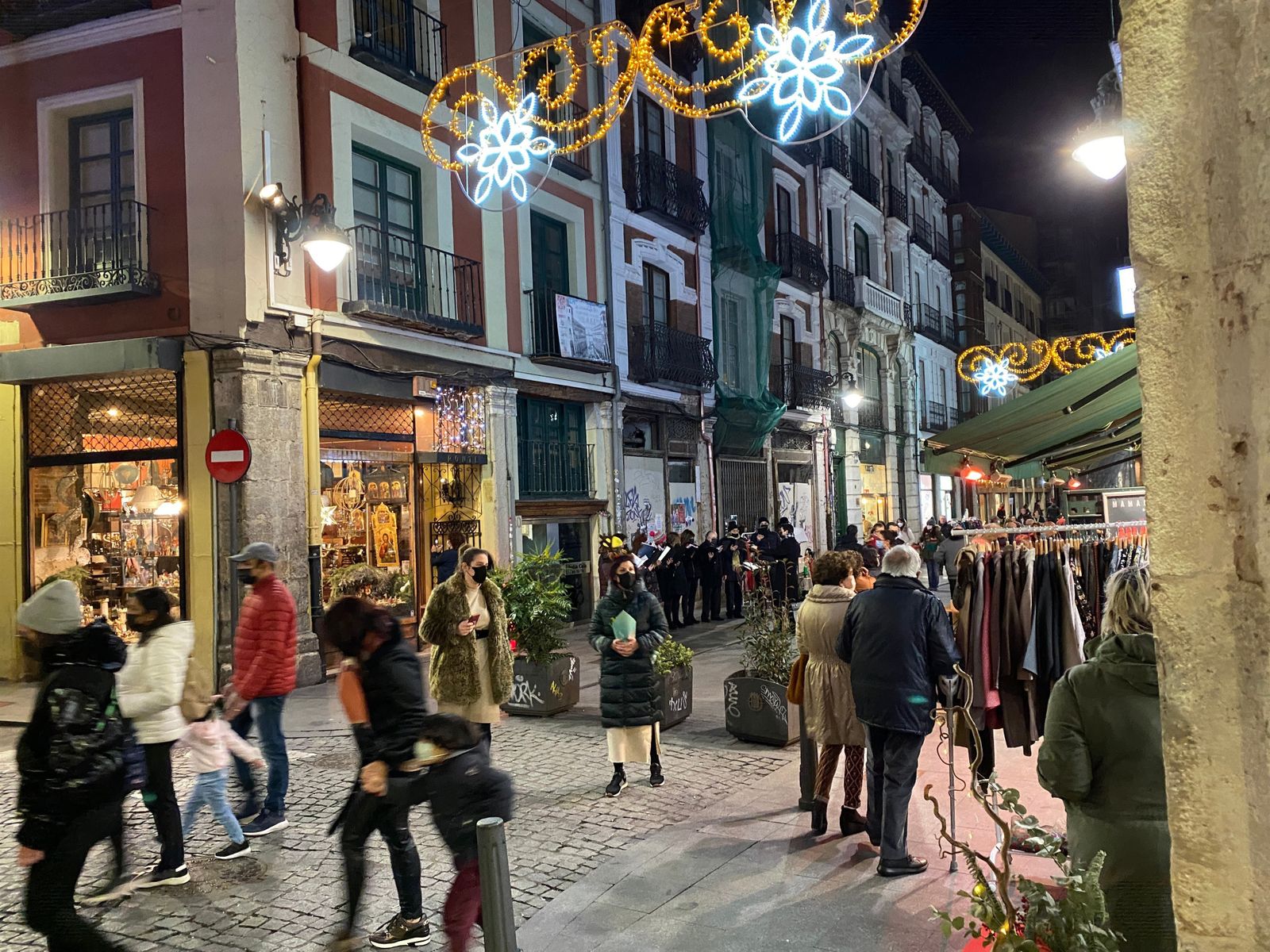 Varias personas caminan por una calle iluminada con luces de Navidad