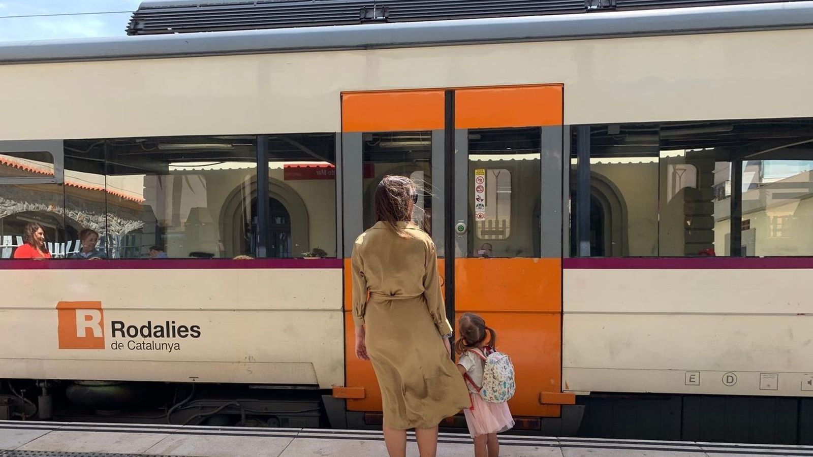 Pasajeros frente a un tren de Rodalies de Cataluña