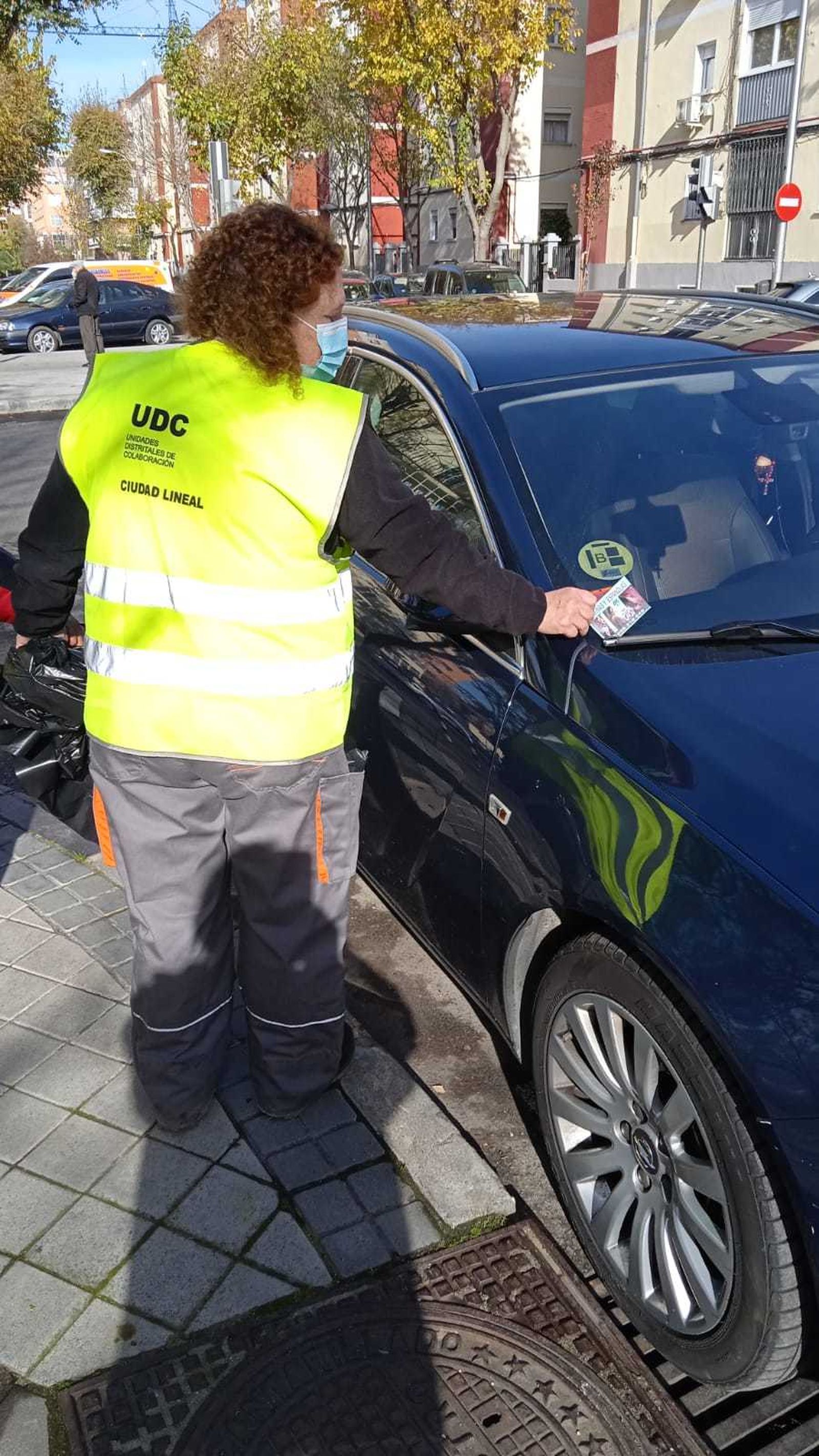 Una mujer quita publicidad de prostitución en un coche de Ciudad Lineal