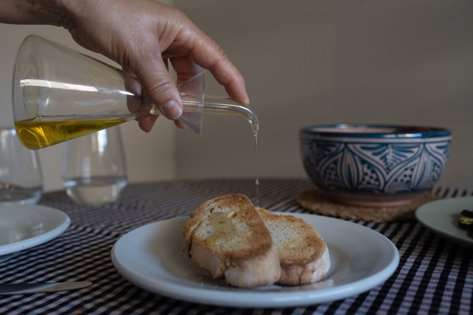 Una persona echa aceite de oliva en una tostada
