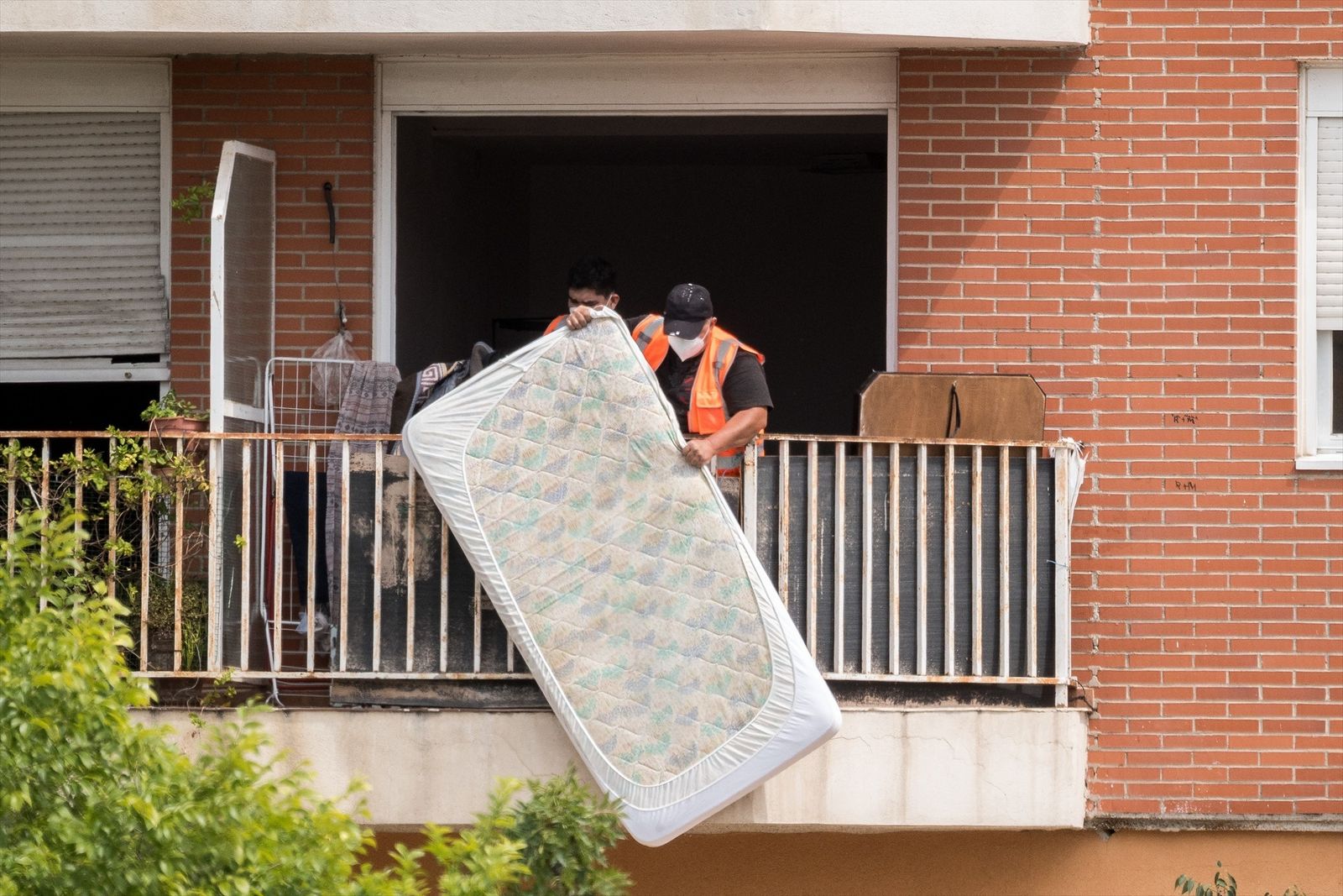 Un trabajador saca un colchón por el balcón durante el desalojo de 60 familias en Alcobendas