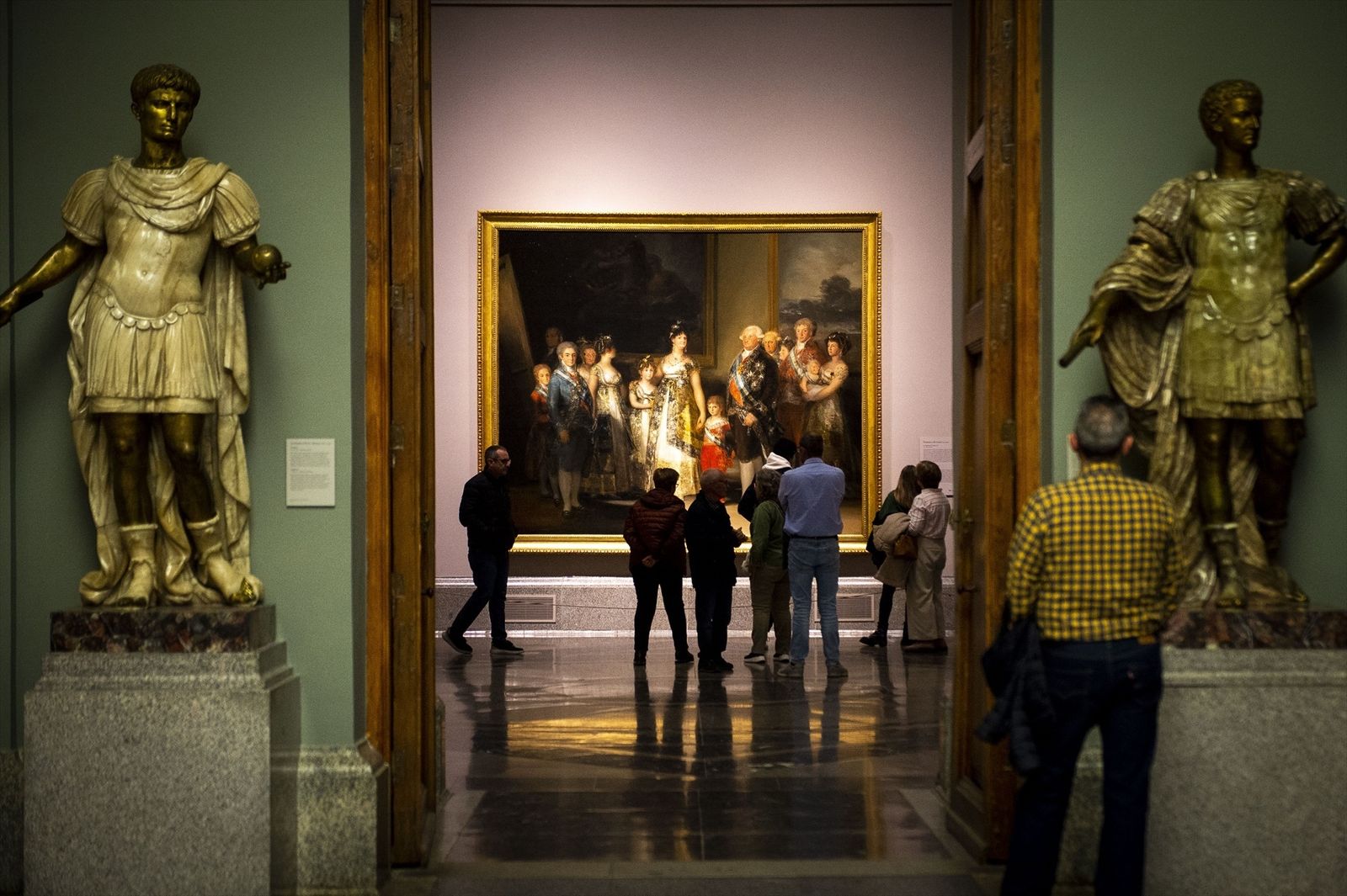 Varias personas observan el cuadro de la familia de Carlos IV de Goya en el Museo del Prado de noche