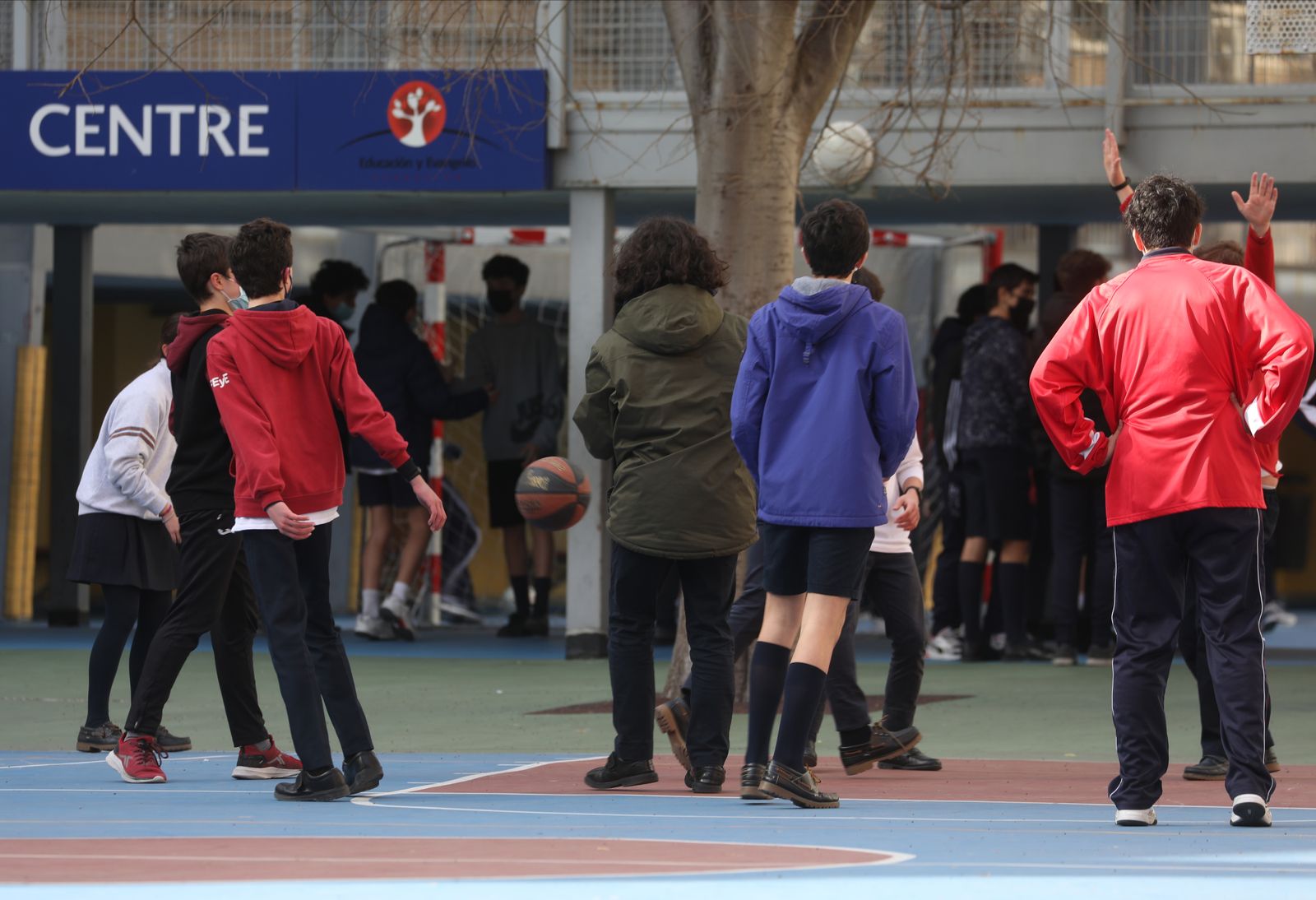 Un grupo de niños juegan al baloncesto en el patio del colegio