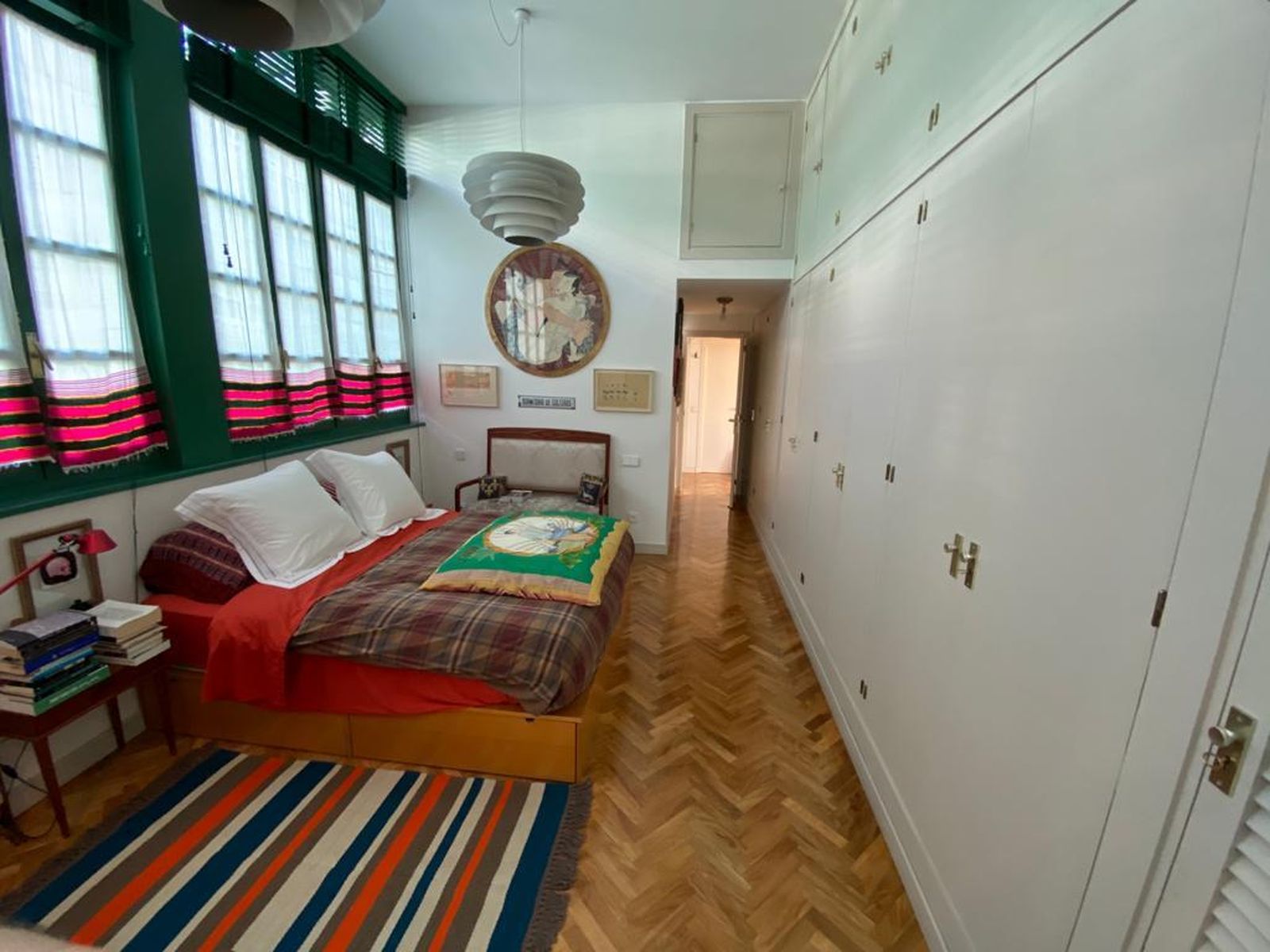 El dormitorio tiene como cabecero una pared repleta de ventanas.