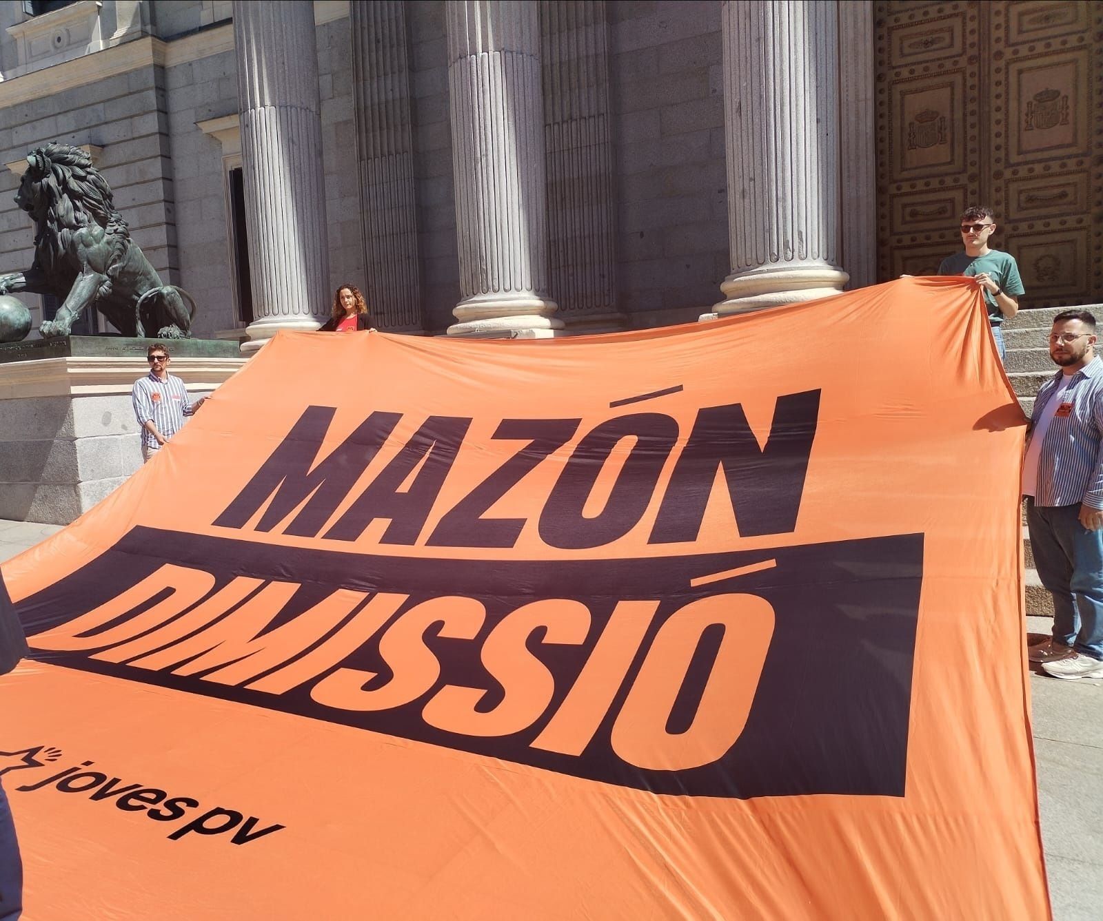 Jóvenes de Compromís despliegan una pancarta en la puerta del Congreso exigiendo la dimisión de Mazón