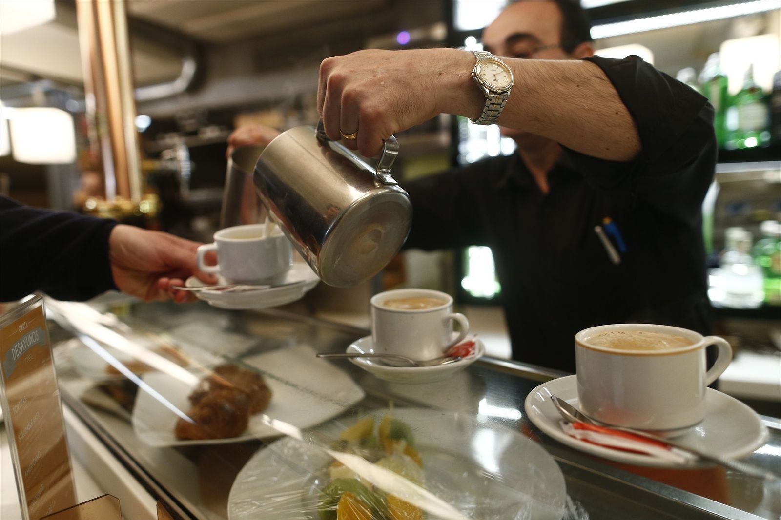 Un camarero sirve cafés con leche