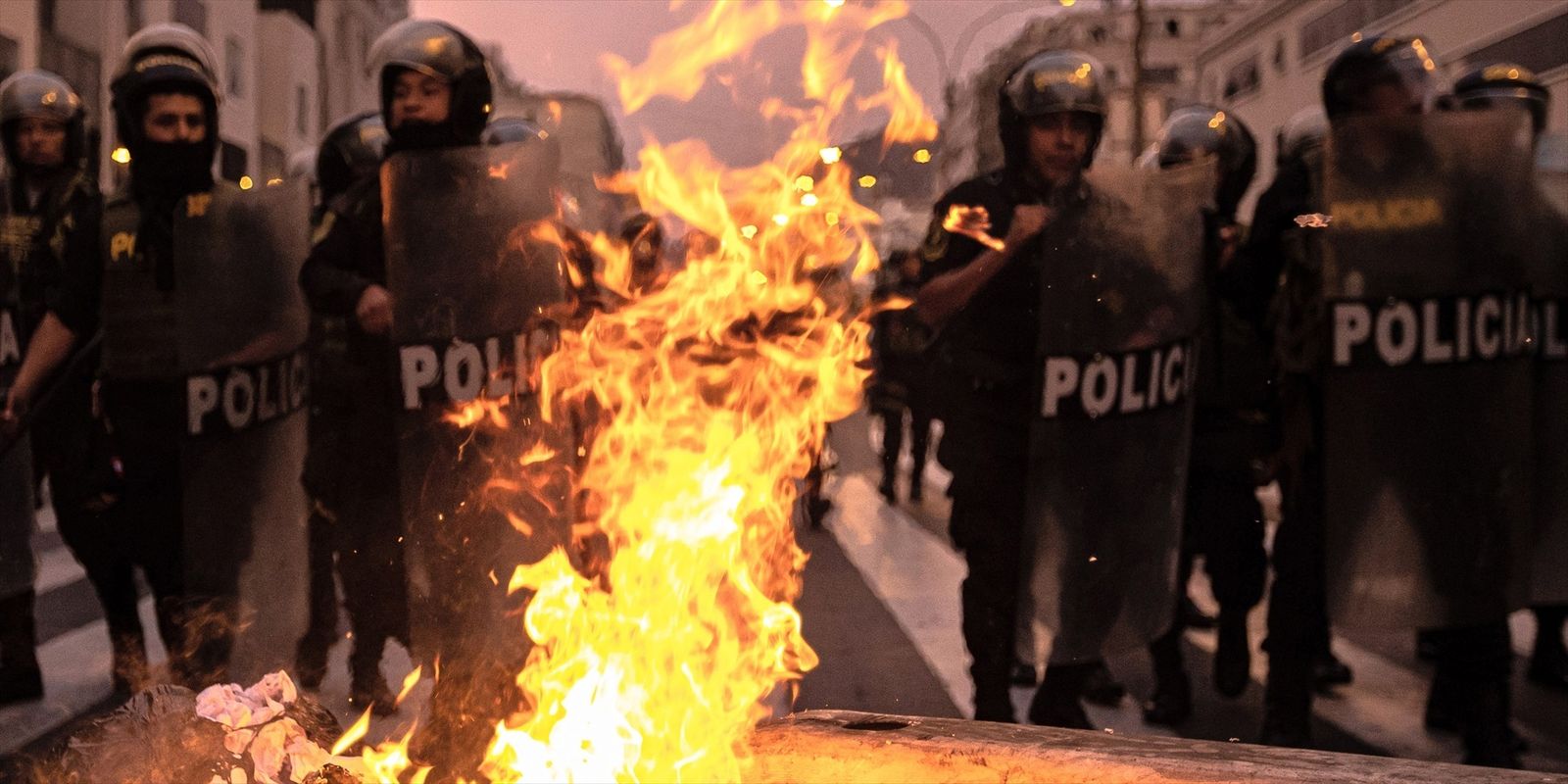 Oficiales de policía detrás de barricadas en llamas encendidas por simpatizantes del derrocado presidente Castillo de Perú